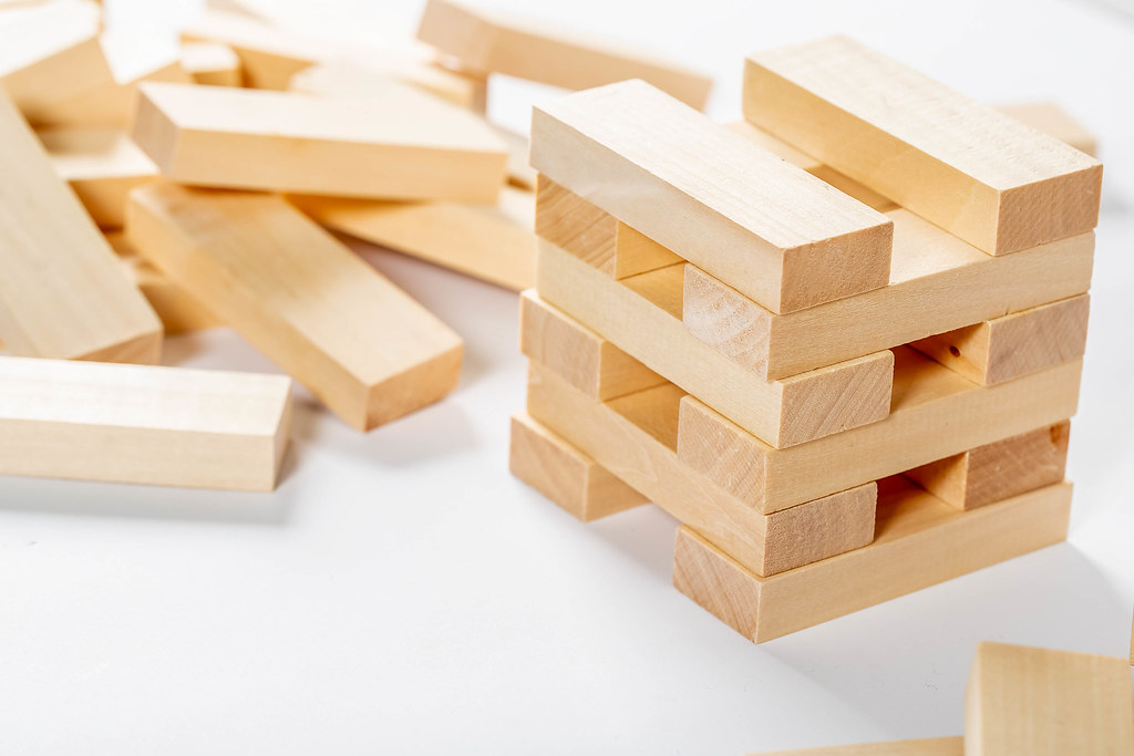 A Jenga Tower And Wooden Bricks On White Background