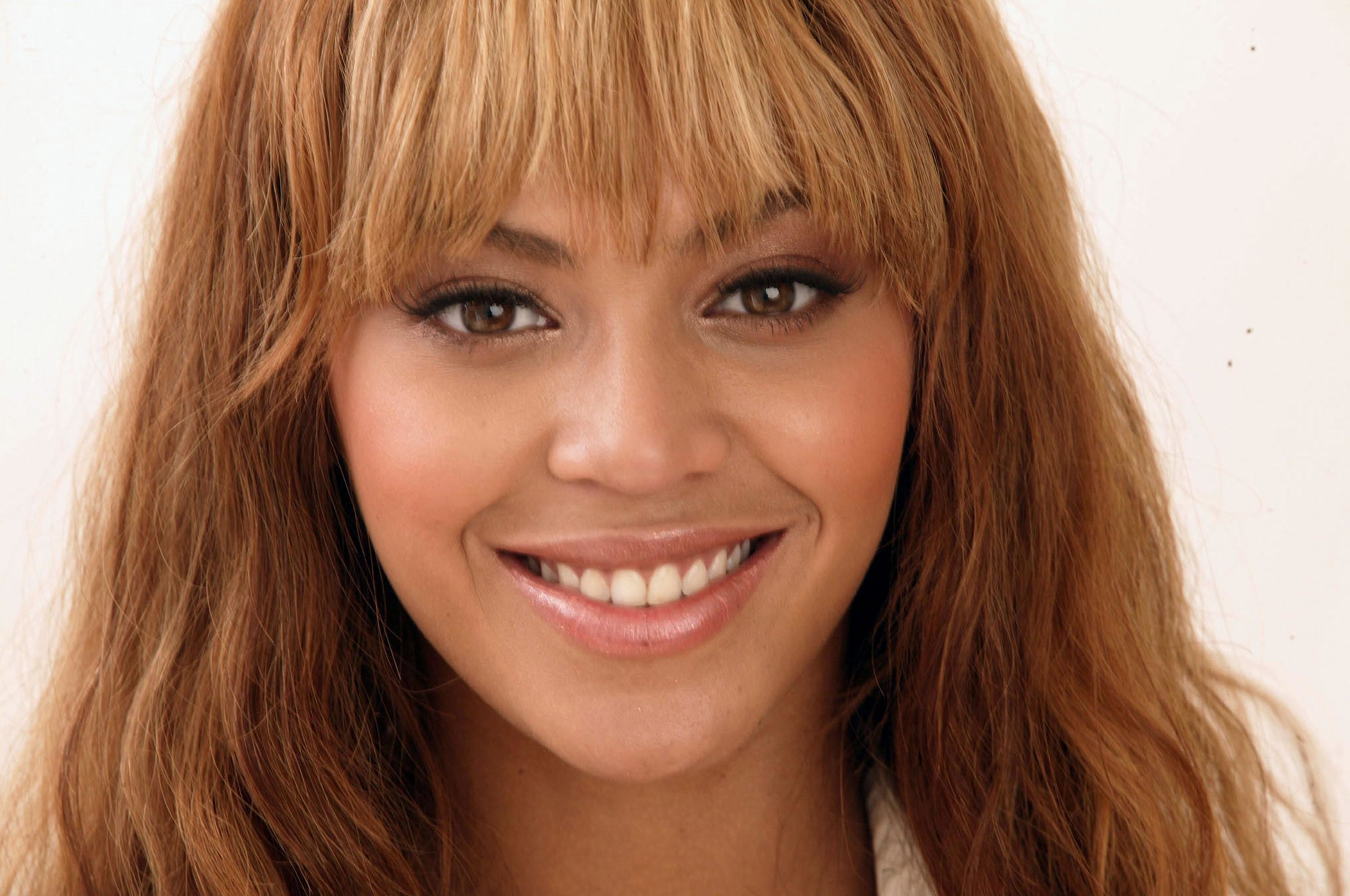 Close-up of Beyonce Knowles-Carter, showcasing her radiant smile and honey-blonde hair with wispy bangs