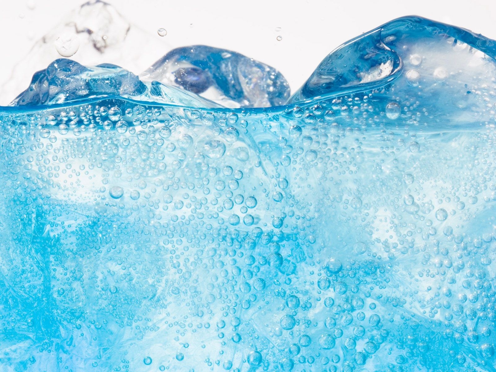 Close-up of ice cubes in sparkling blue water with bubbles