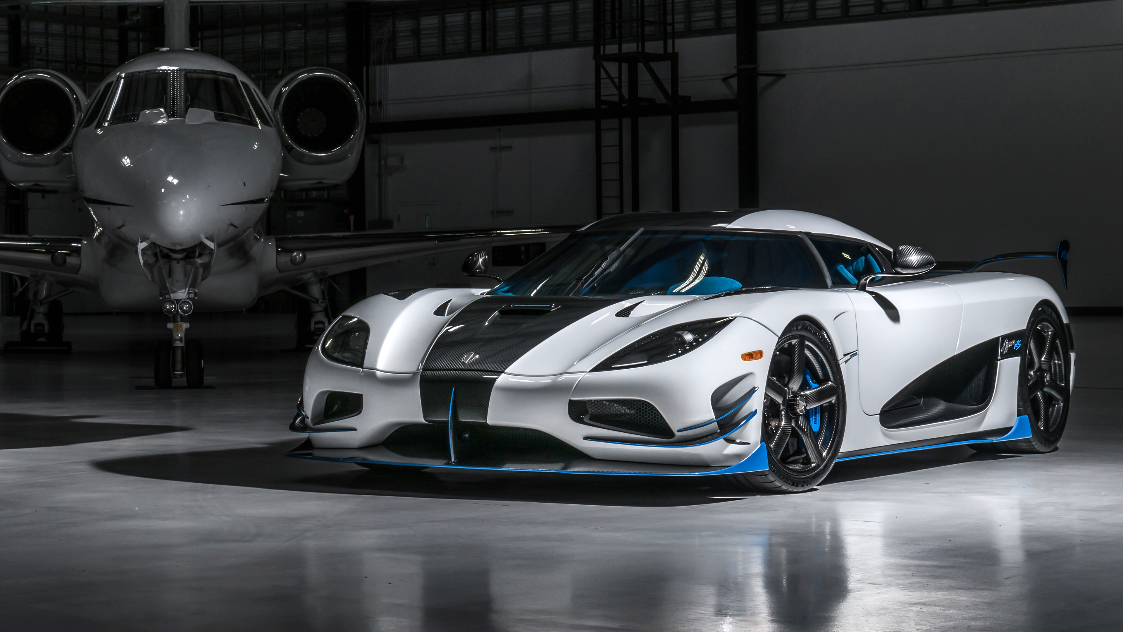 White and Black Koenigsegg Jesko in a hangar with private jet