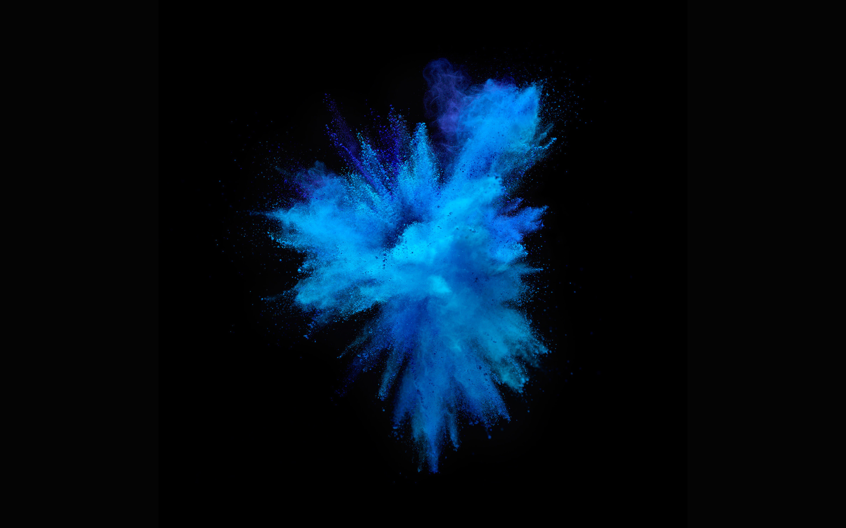 A vibrant explosion of blue powder on a black background, reminiscent of the dynamic and colorful MacBook Pro wallpapers