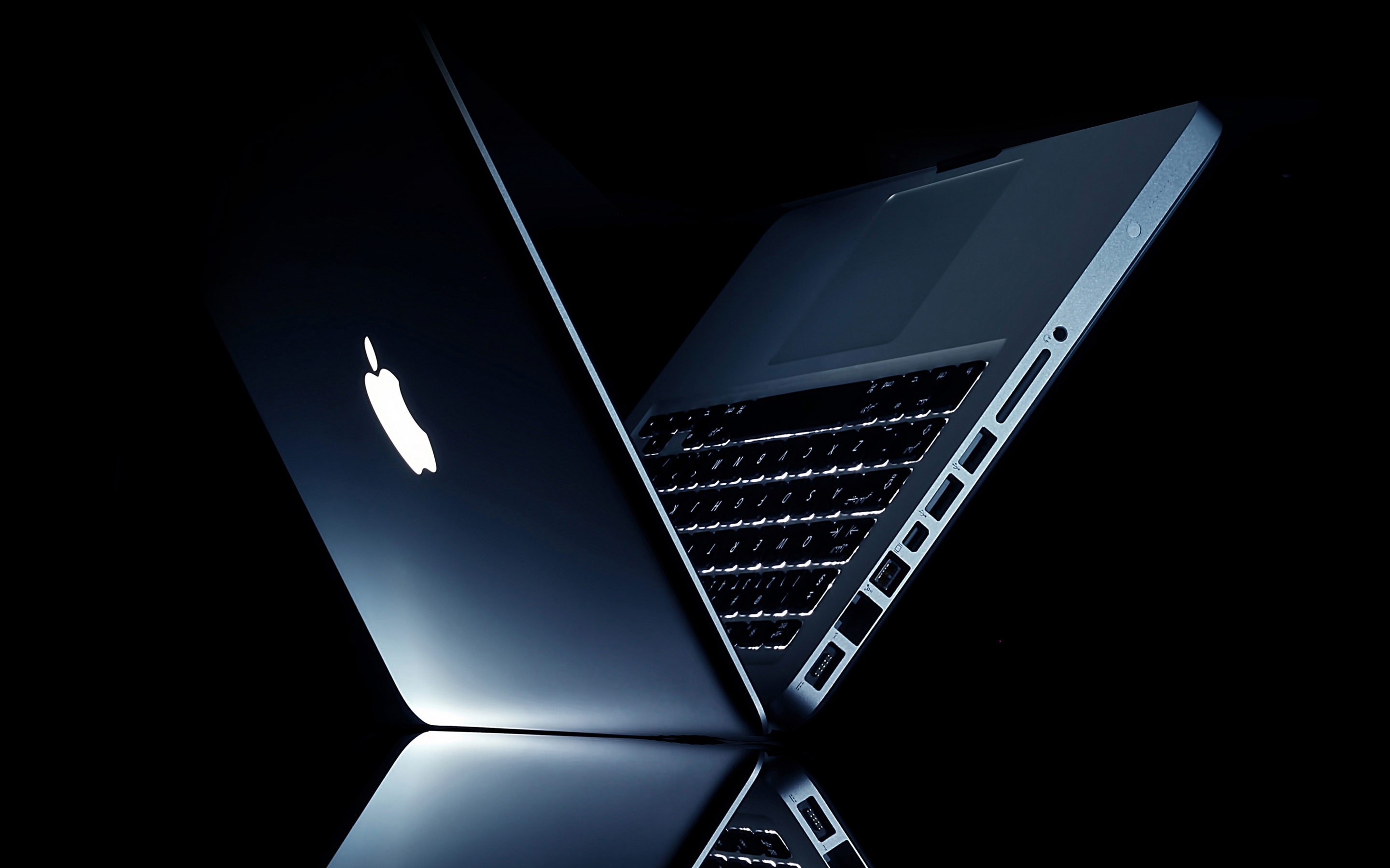 Sleek and stylish Apple MacBook laptop in dark background, showcasing its minimalist design and illuminated Apple logo