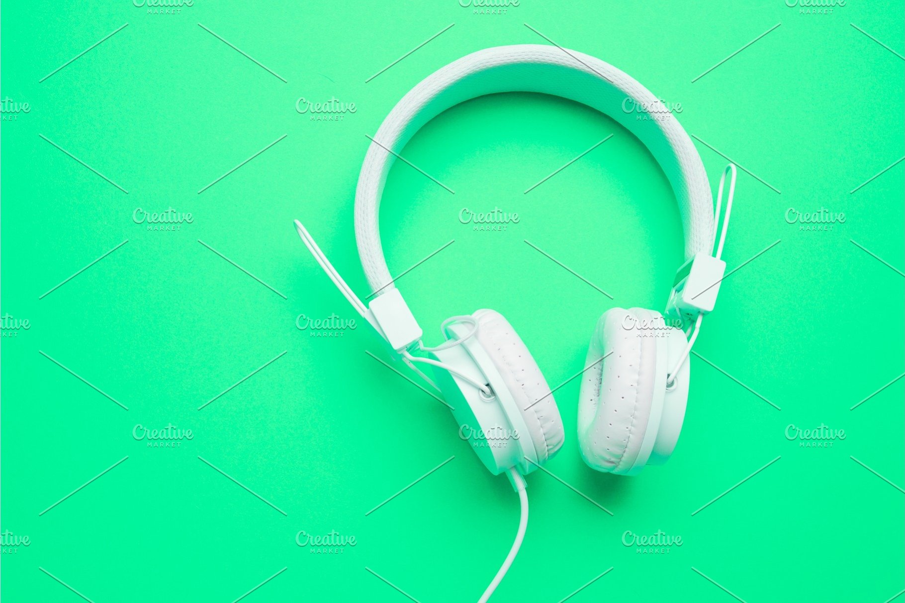 White Headphones With Cord On An Empty Green Background