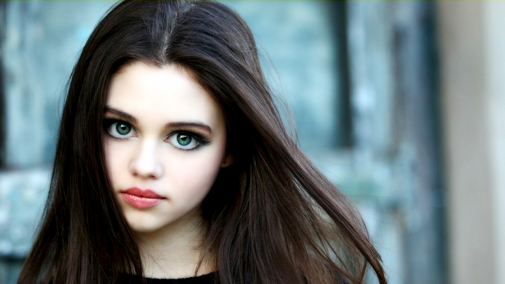 Close-up portrait of a young girl with long, dark hair and captivating green eyes