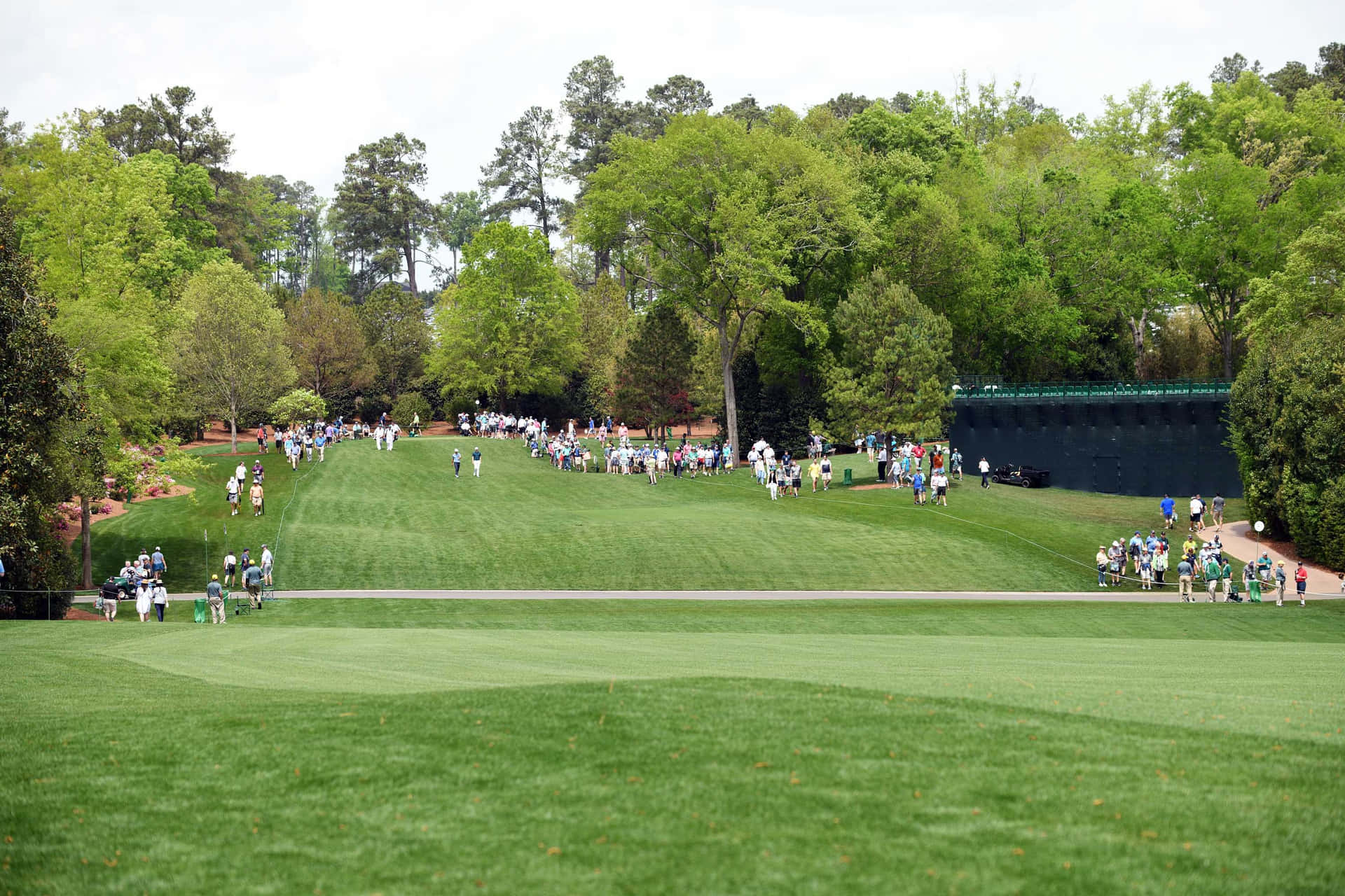 A Group Of People Walking Down Green Golf Course Wallpaper