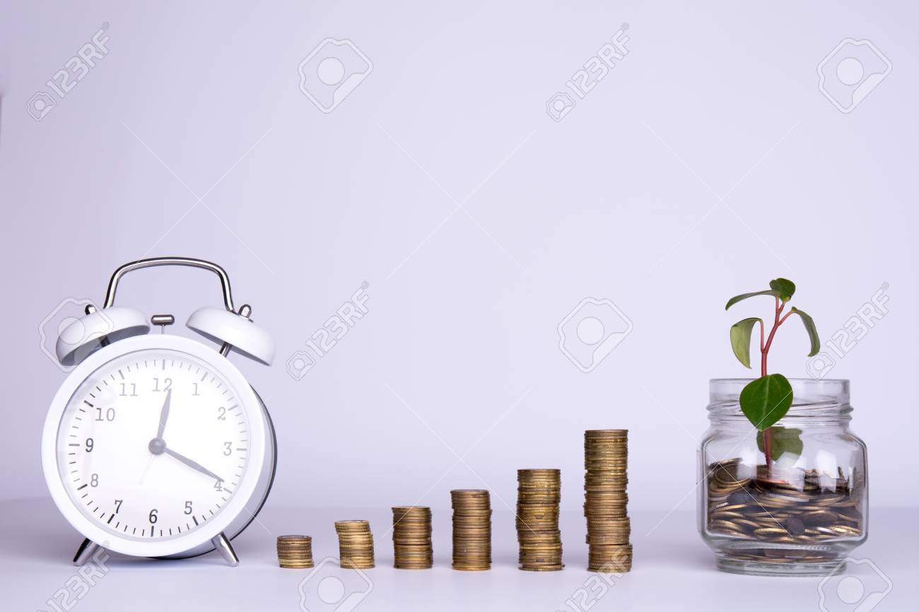 Saved Money And A Clock On White Background Stock Photo