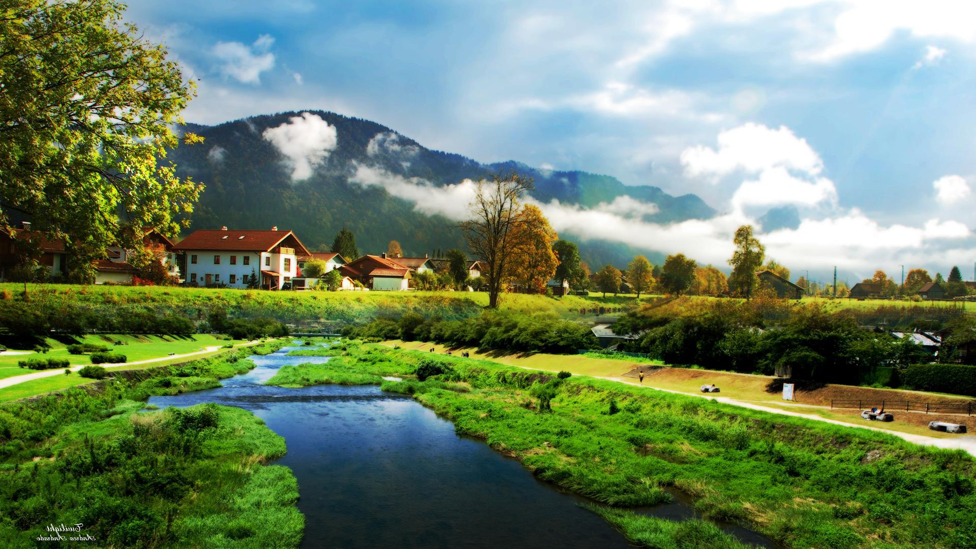 Scenic landscape with a river, houses, mountains, trees, and clouds, perfect for a beautiful wallpaper