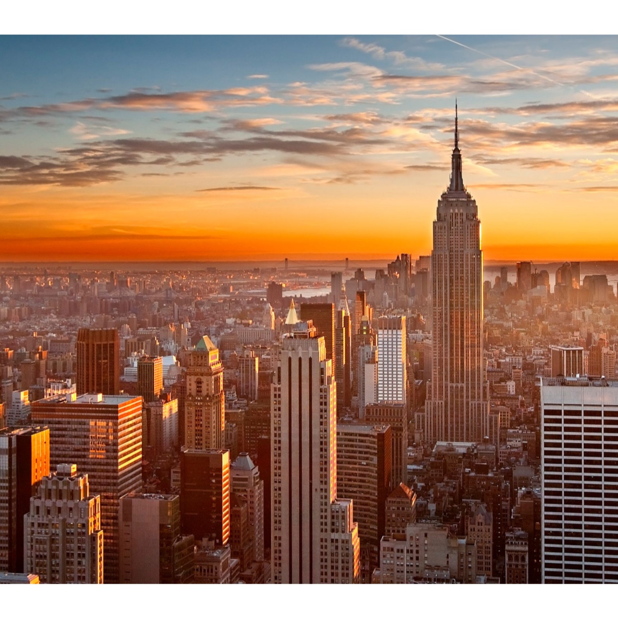 A stunning sunset over the New York City skyline, featuring the iconic Empire State Building