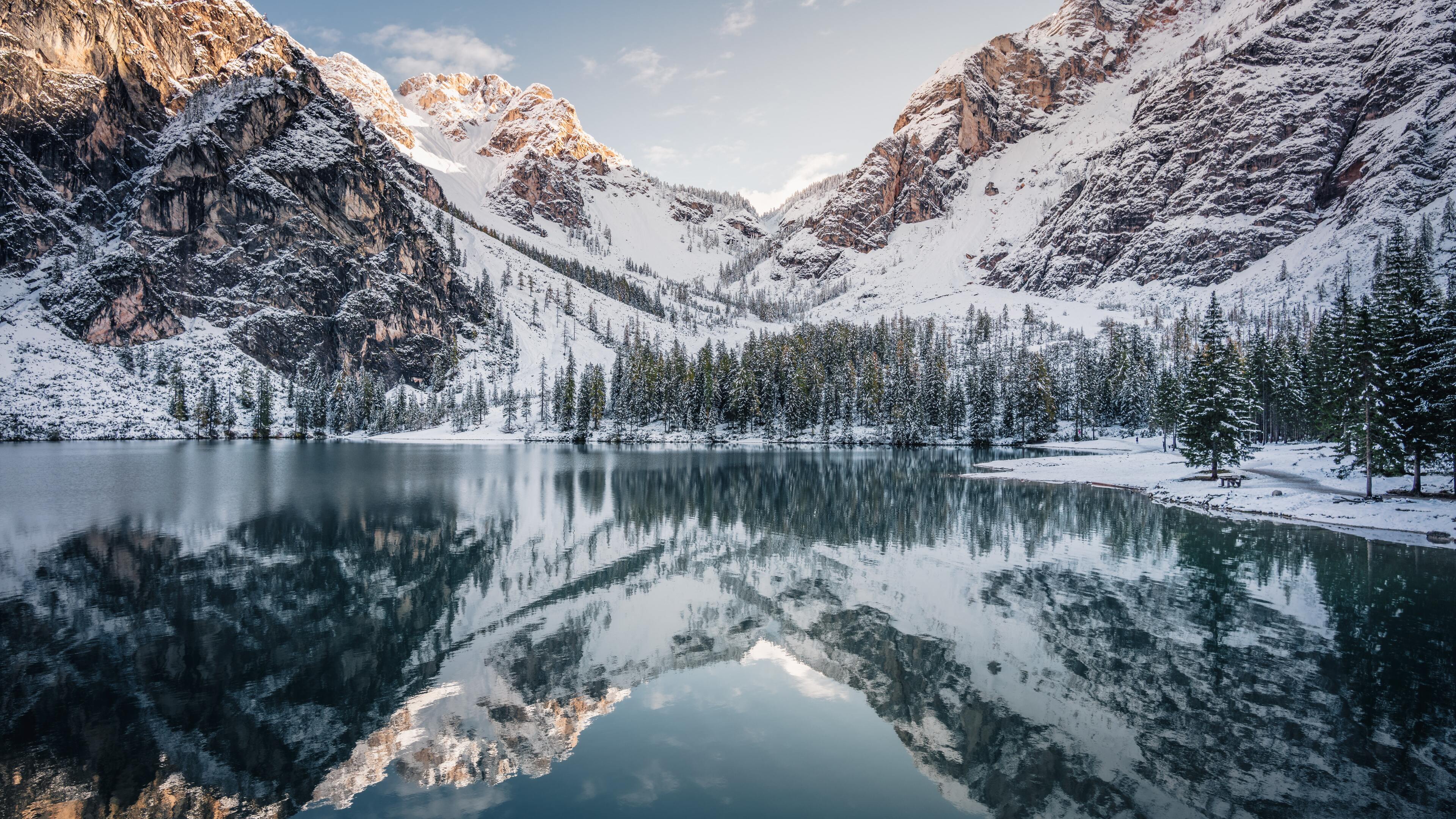Serene winter landscape with snow-capped mountains reflected in a calm lake