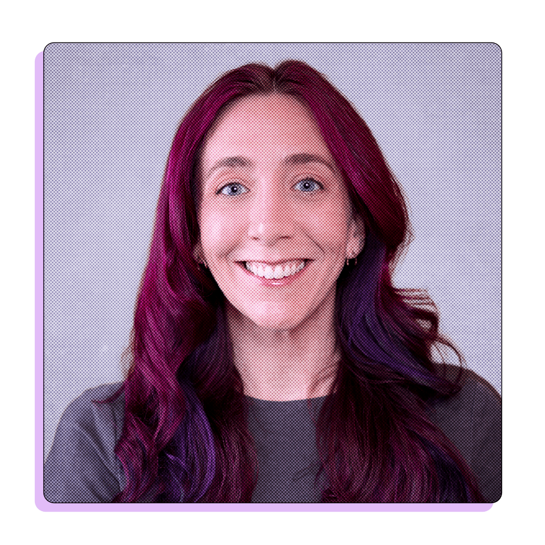 Portrait of a woman with long, vibrant purple hair, smiling warmly at the camera