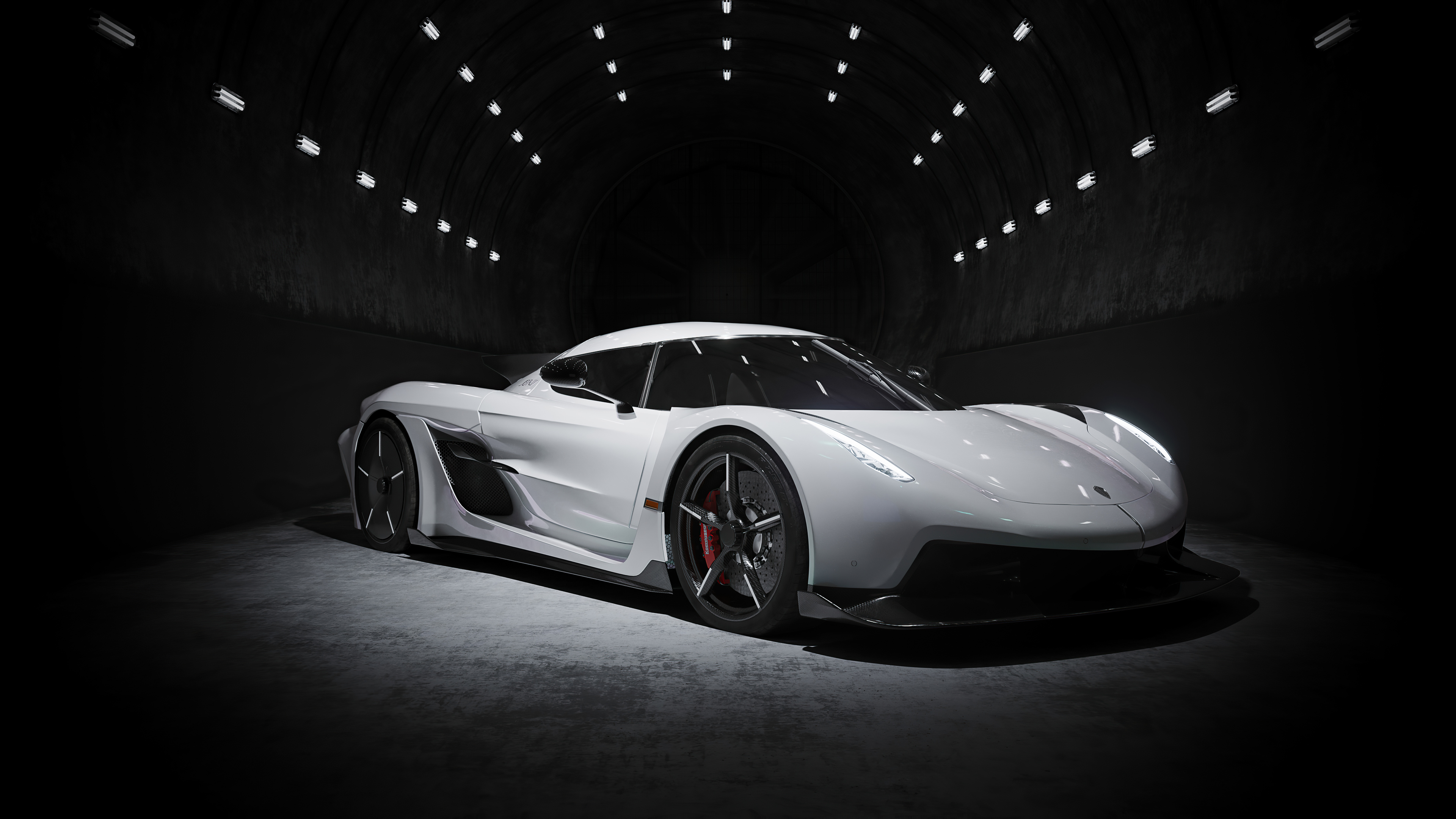 A white Koenigsegg Gemera dramatically lit within a dark tunnel, showcasing its sleek design and powerful presence