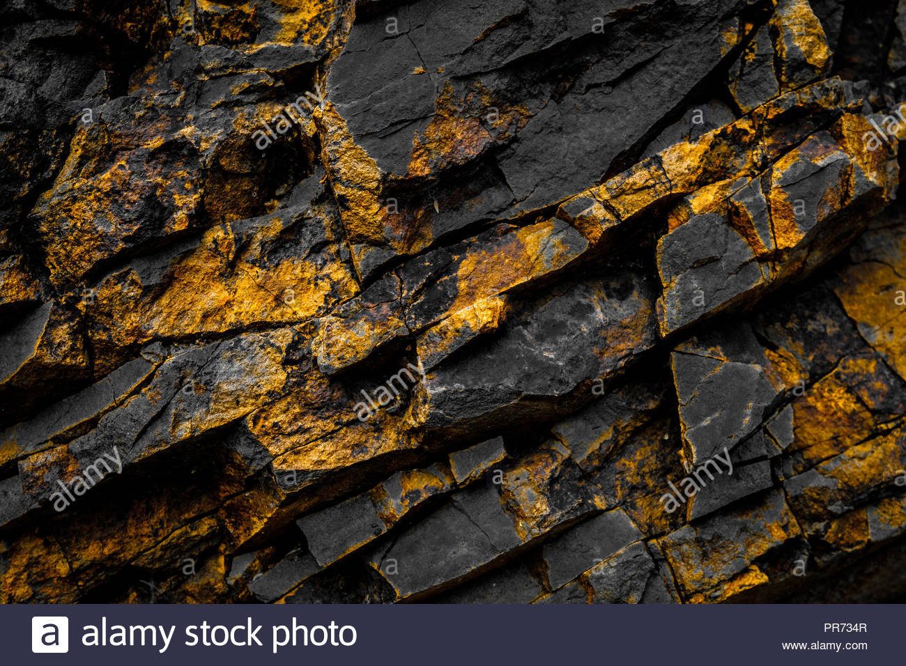Black Rock Background With Gold Yellow Colored Rocks Stock Photo