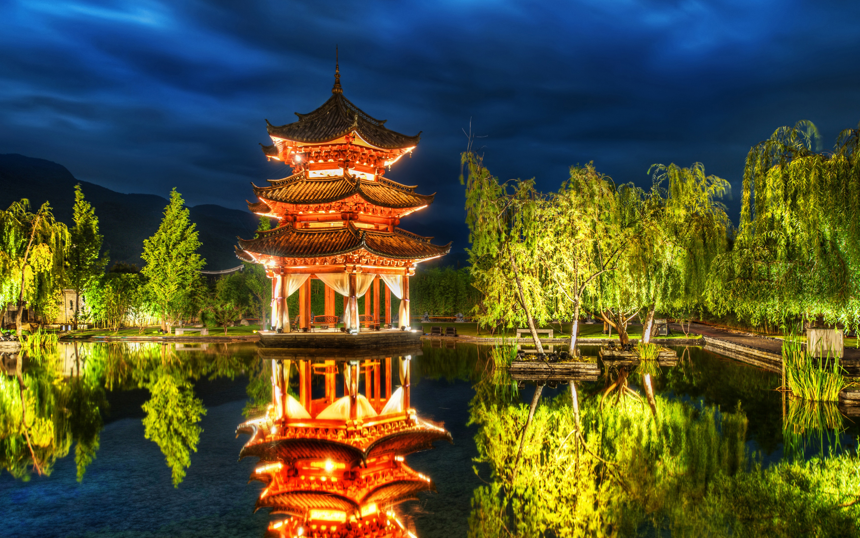 A stunning night view of a traditional Chinese pagoda reflected in a serene pond, illuminated by warm lights