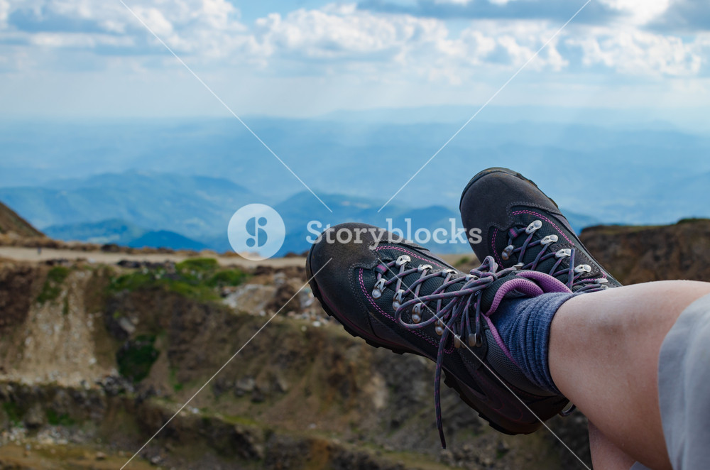 Legs In Trekking Shoes With Mountain Landscape A Background