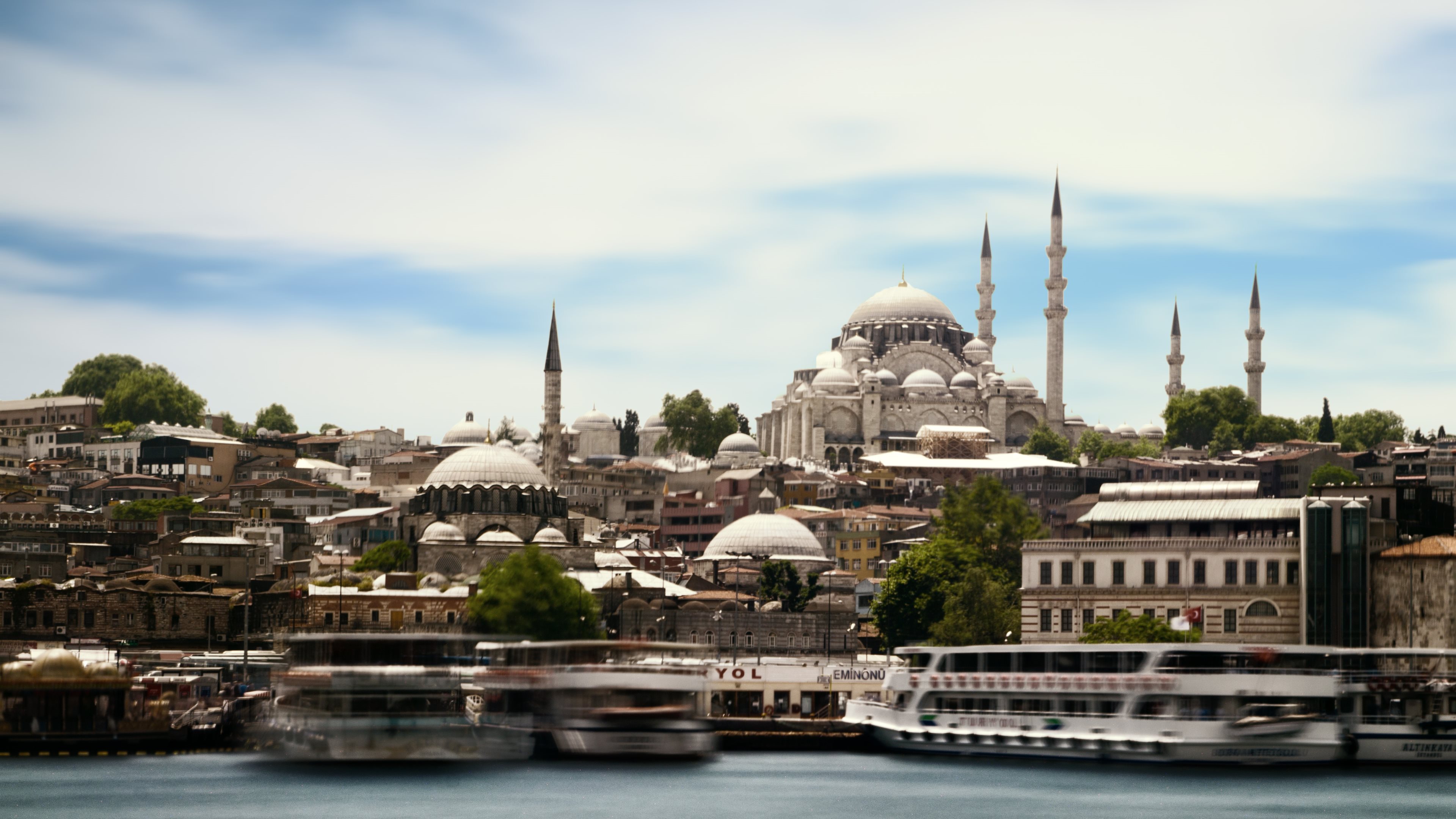 A scenic view of the Süleymaniye Mosque in Istanbul, Turkey, overlooking the Bosphorus Strait with traditional boats in the foreground
