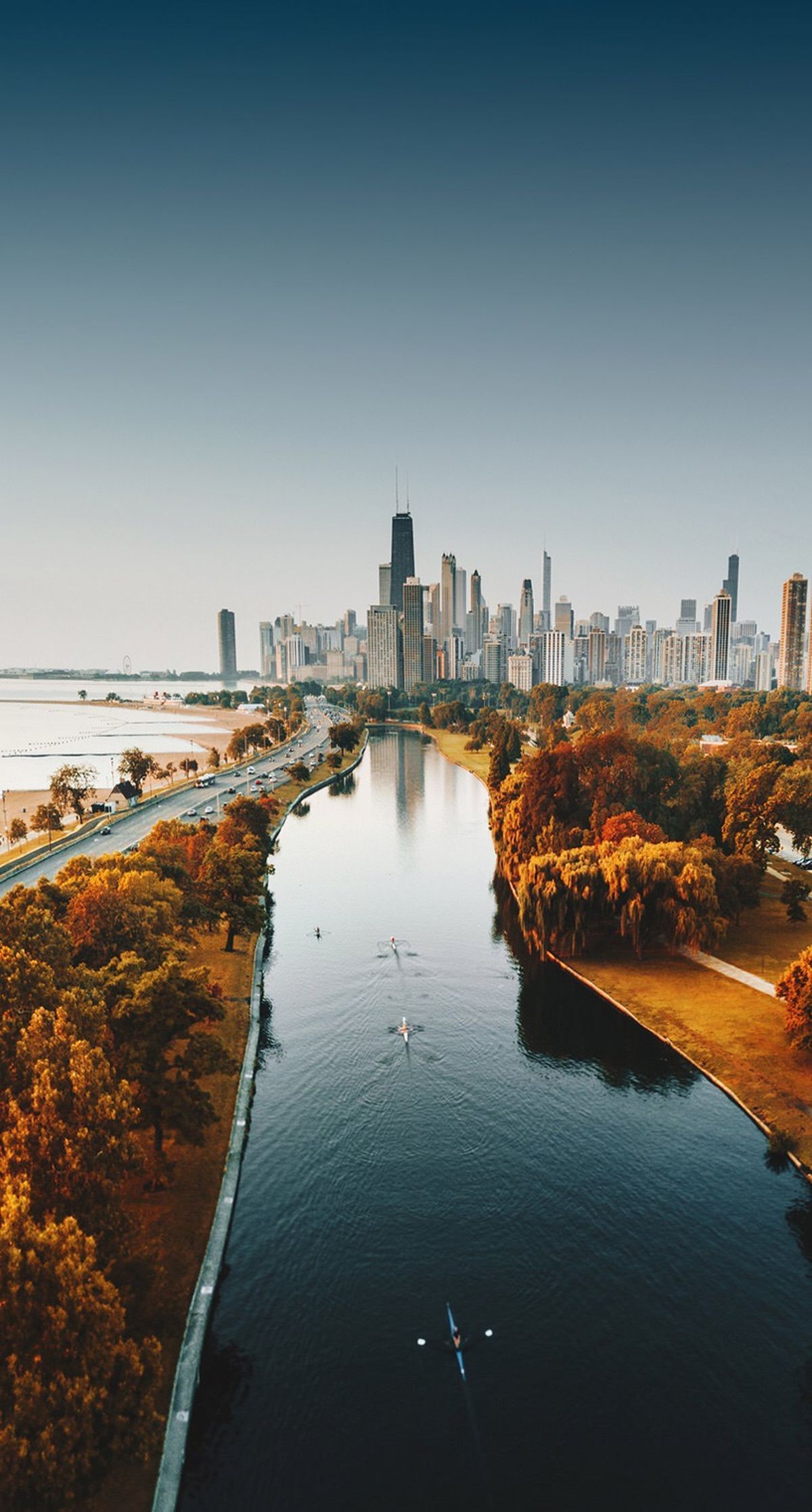 Aerial view of Chicago skyline and river with kayakers at sunset, showcasing autumn foliage and tranquil waters