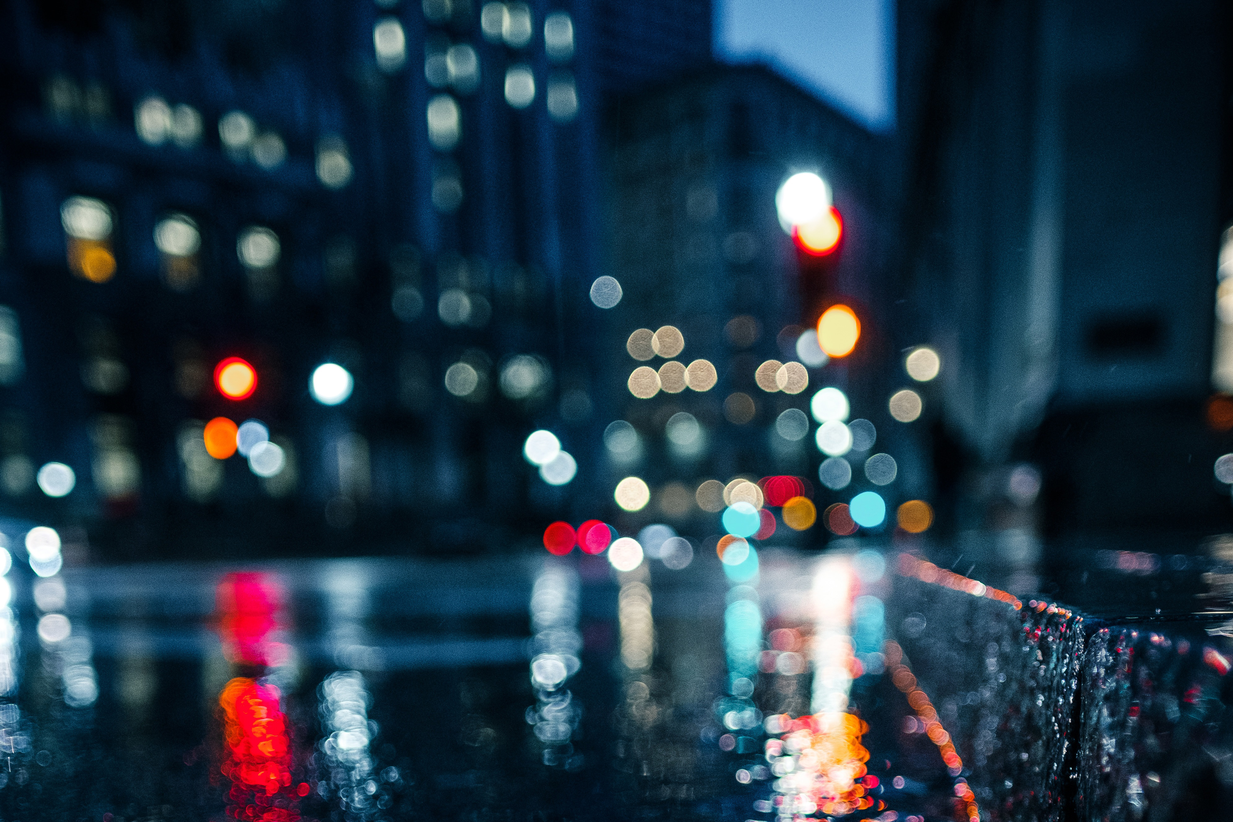 Bokeh effect of city lights reflecting on a wet street at night, creating a dreamy rainy cityscape wallpaper
