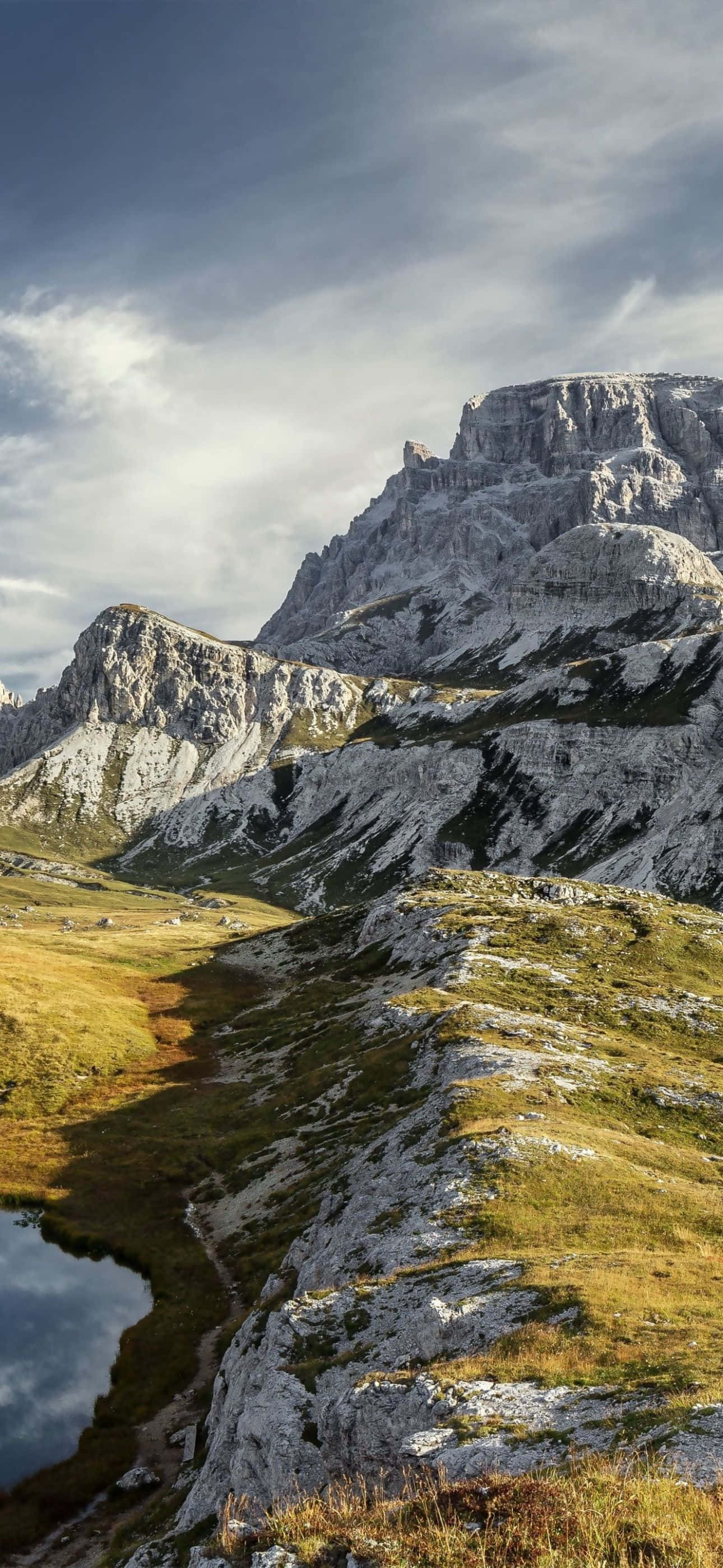 Stunning iPhone 14 Pro Max wallpaper showcasing a majestic mountain range under a dynamic sky. The rugged peaks and the vibrant colors of the landscape make it an ideal background for your device