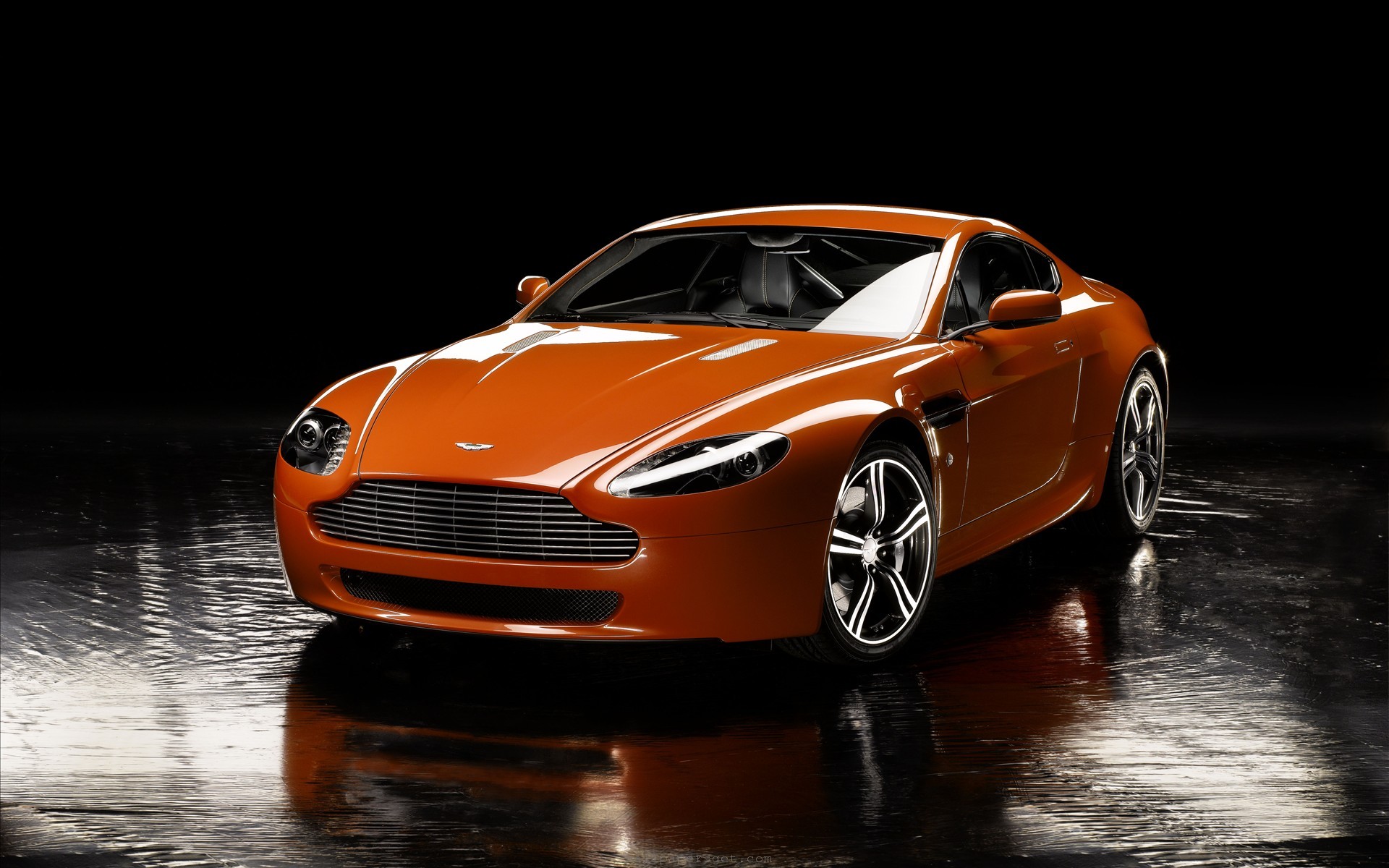 Sleek Orange Aston Martin Vantage on a Dark Reflective Surface