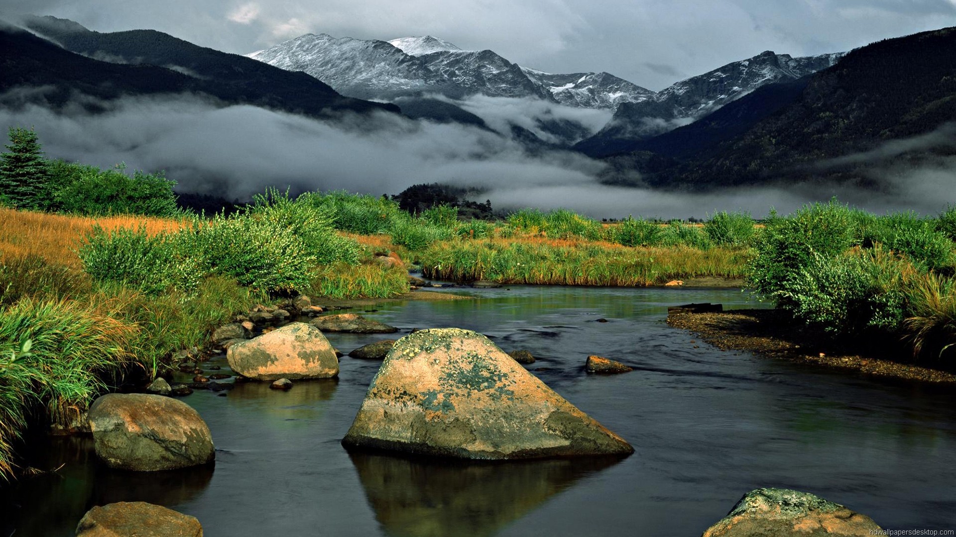 Serene mountain landscape with a flowing river and misty peaks in the background