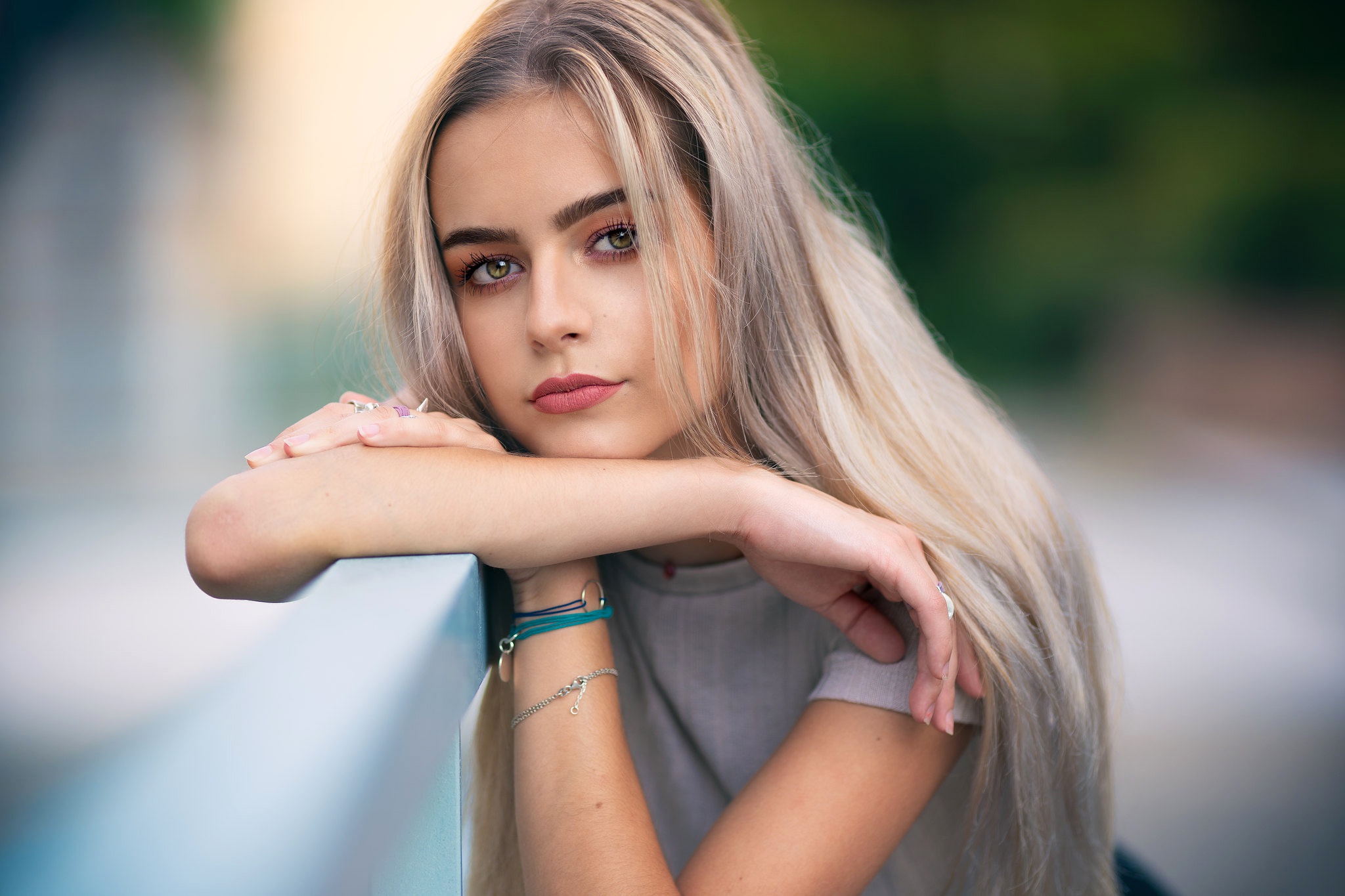 Beautiful blonde girl with green eyes leaning on a railing