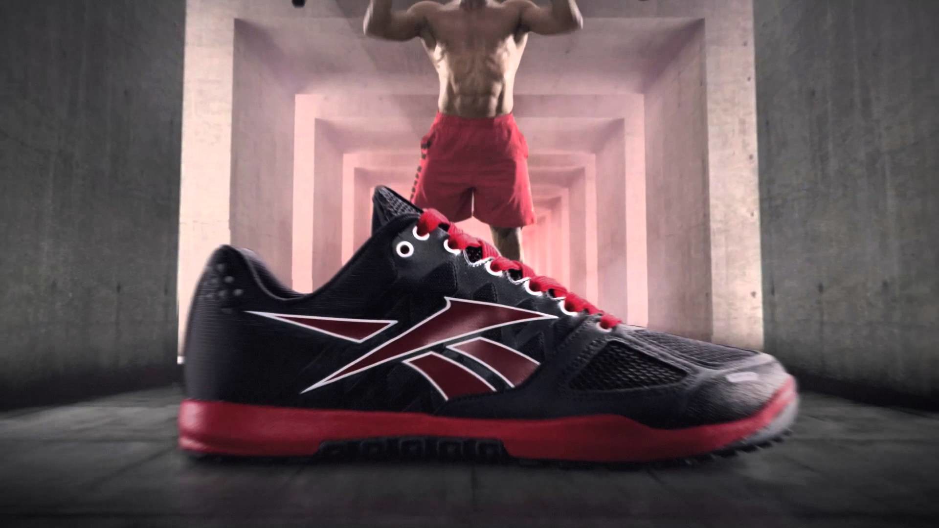 Close-up of a Reebok CrossFit Nano shoe with a man performing a CrossFit exercise in the background