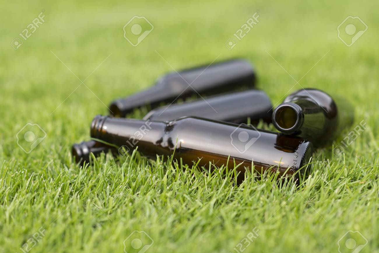 Empty Beer Bottles In A Grass Field With Vague Background Stock