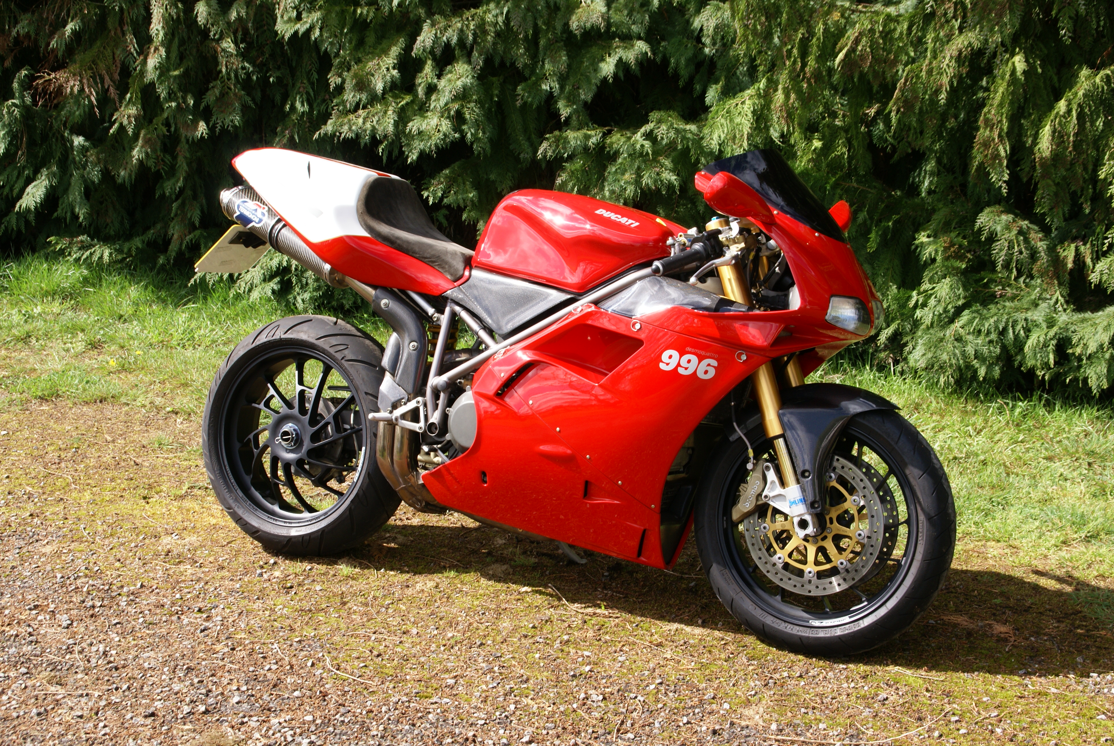 Red Ducati 996 sportbike parked on a gravel path, showcasing its sleek design and racing heritage