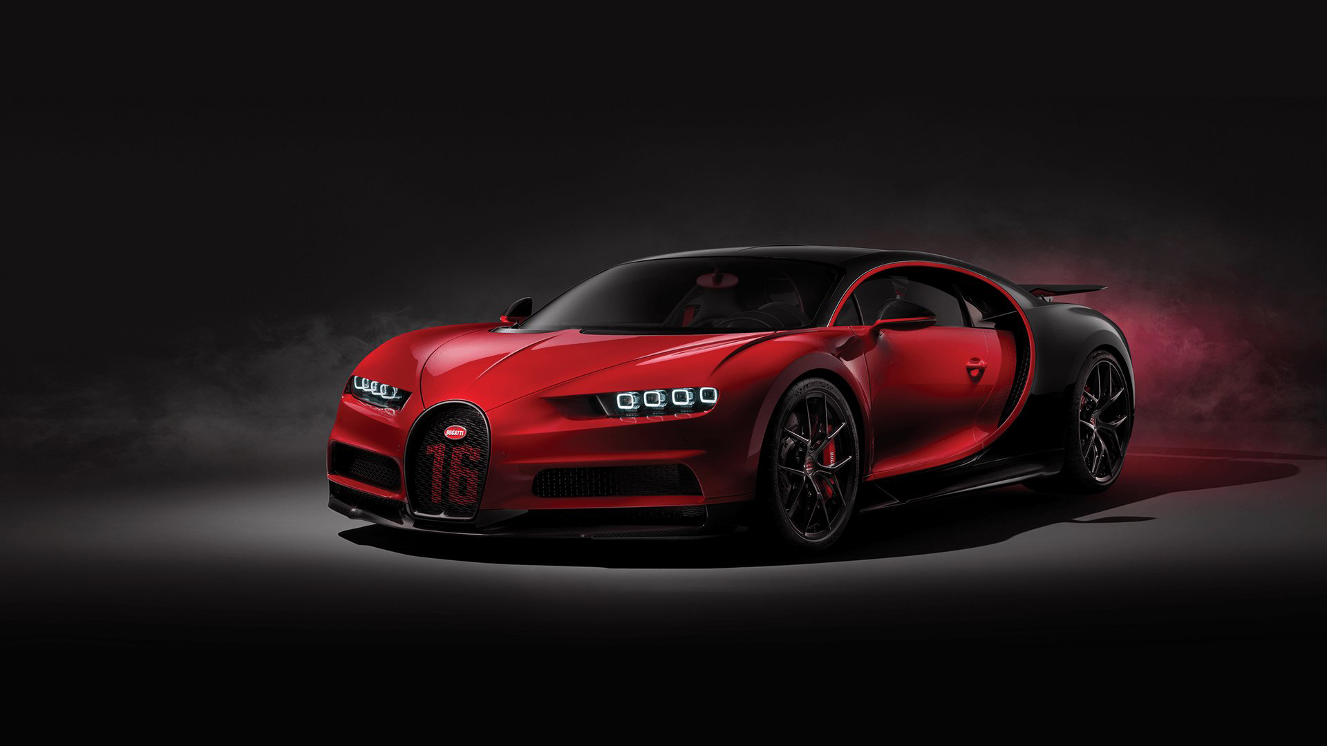 A sleek, red and black Bugatti Chiron sports car against a dark background