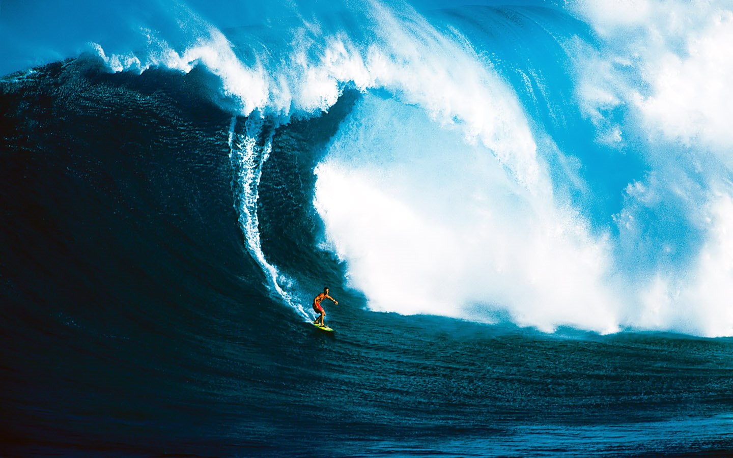 A surfer rides a massive, powerful ocean wave, showcasing the thrill and beauty of surfing