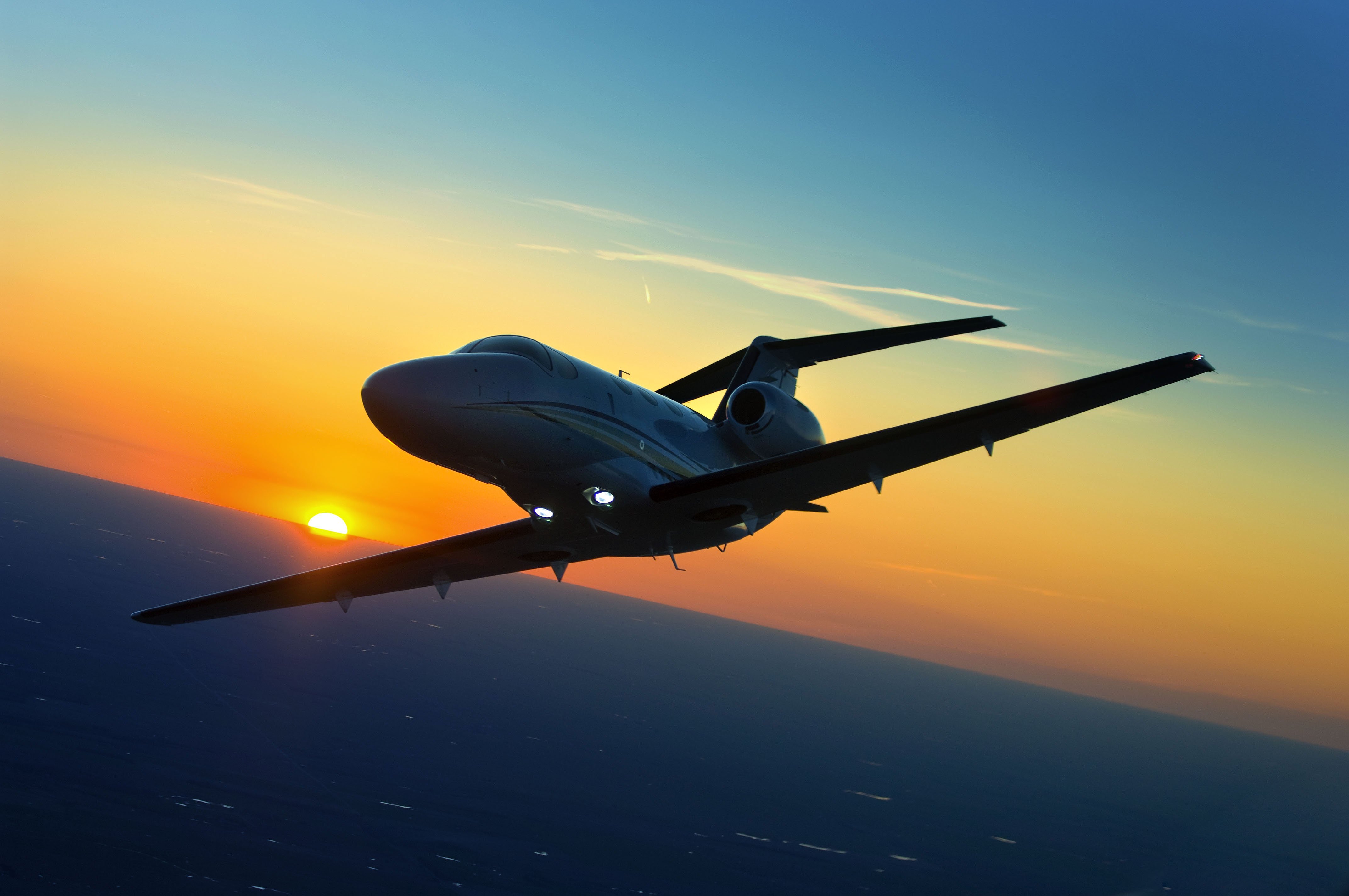 Silhouetted private jet soaring against a vibrant sunset sky