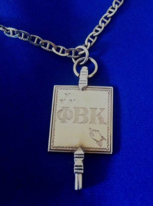 Gold Phi Beta Kappa Key Against Aggie Blue Background