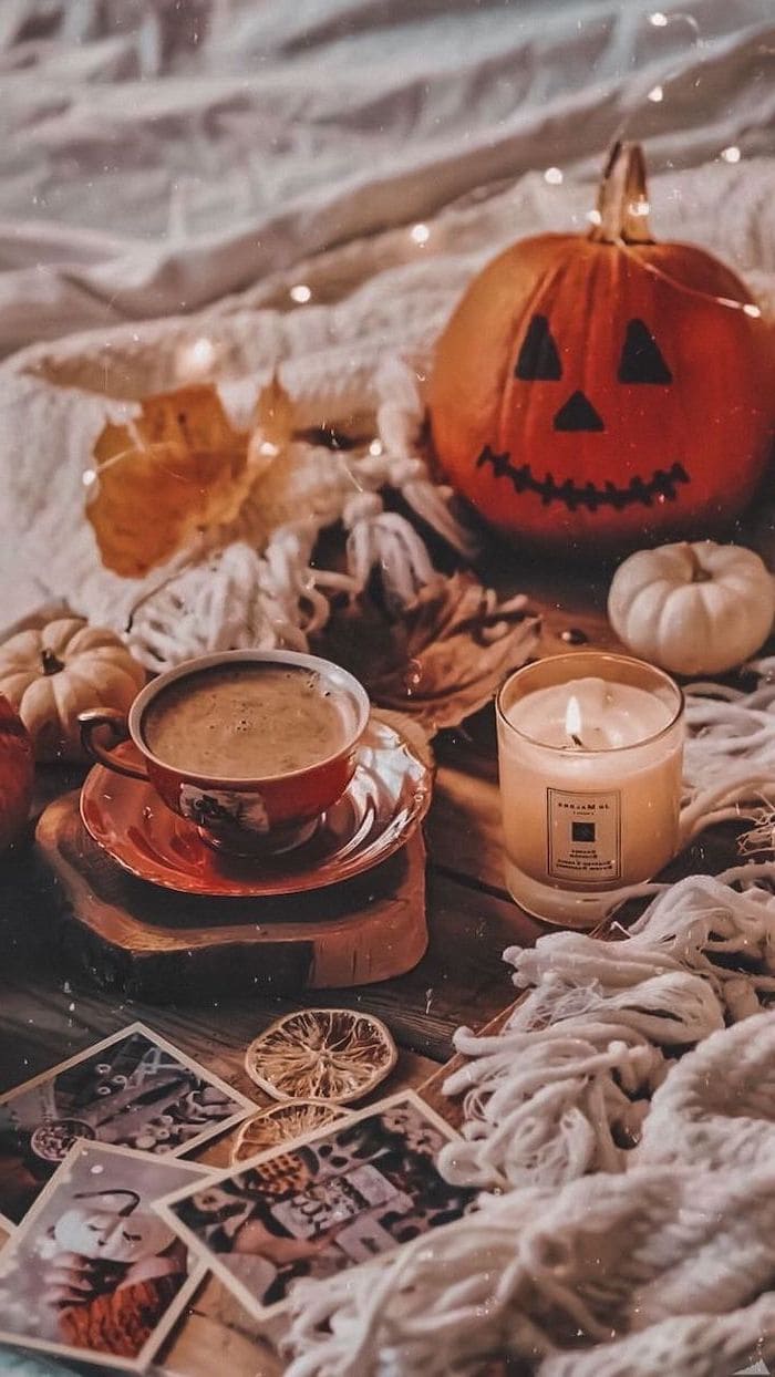 Coffee Cup Next To Lit Candle Carved Pumpkin Placed On Wooden