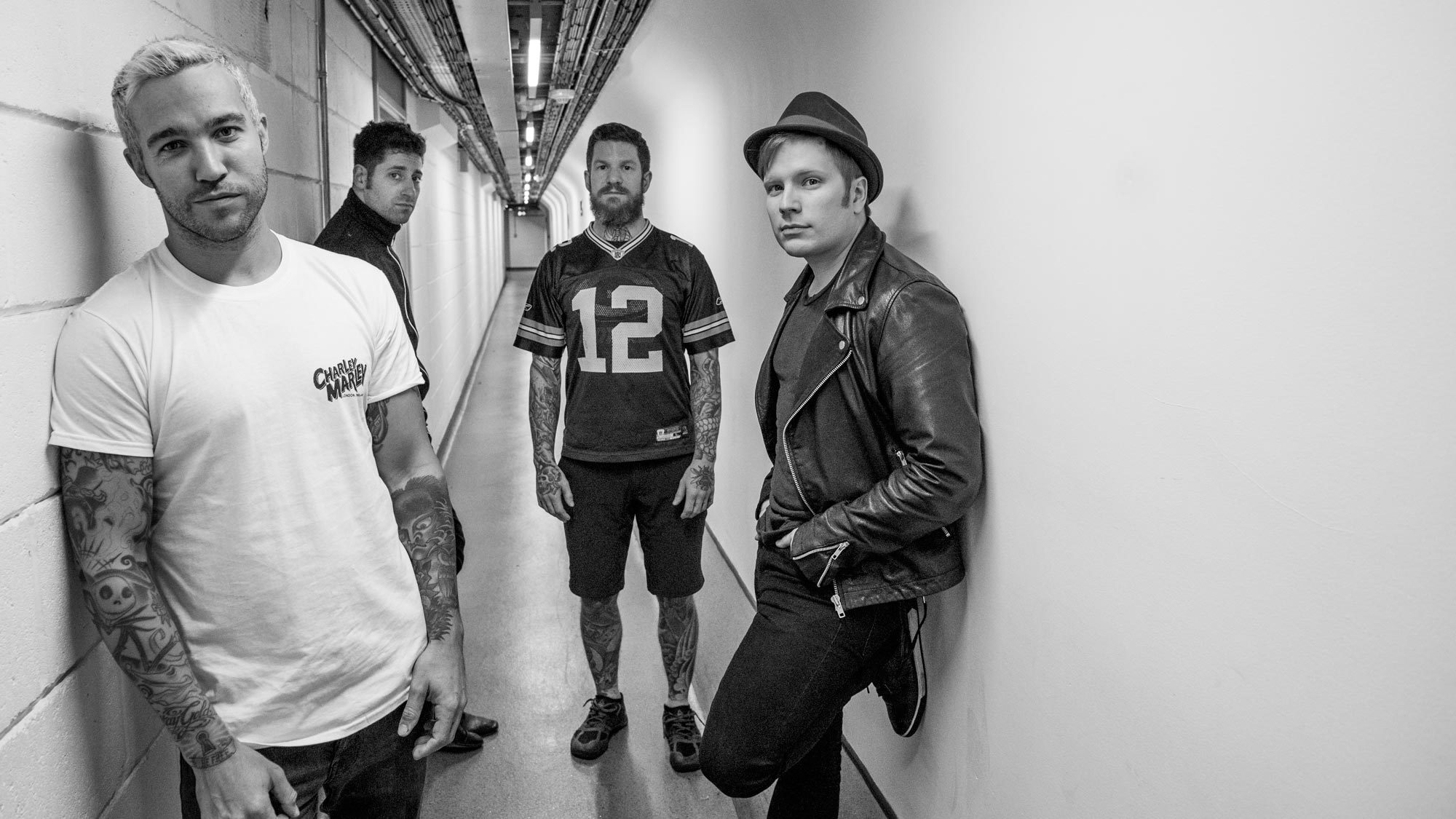 Black and white photo of the band Fall Out Boy posing in a hallway