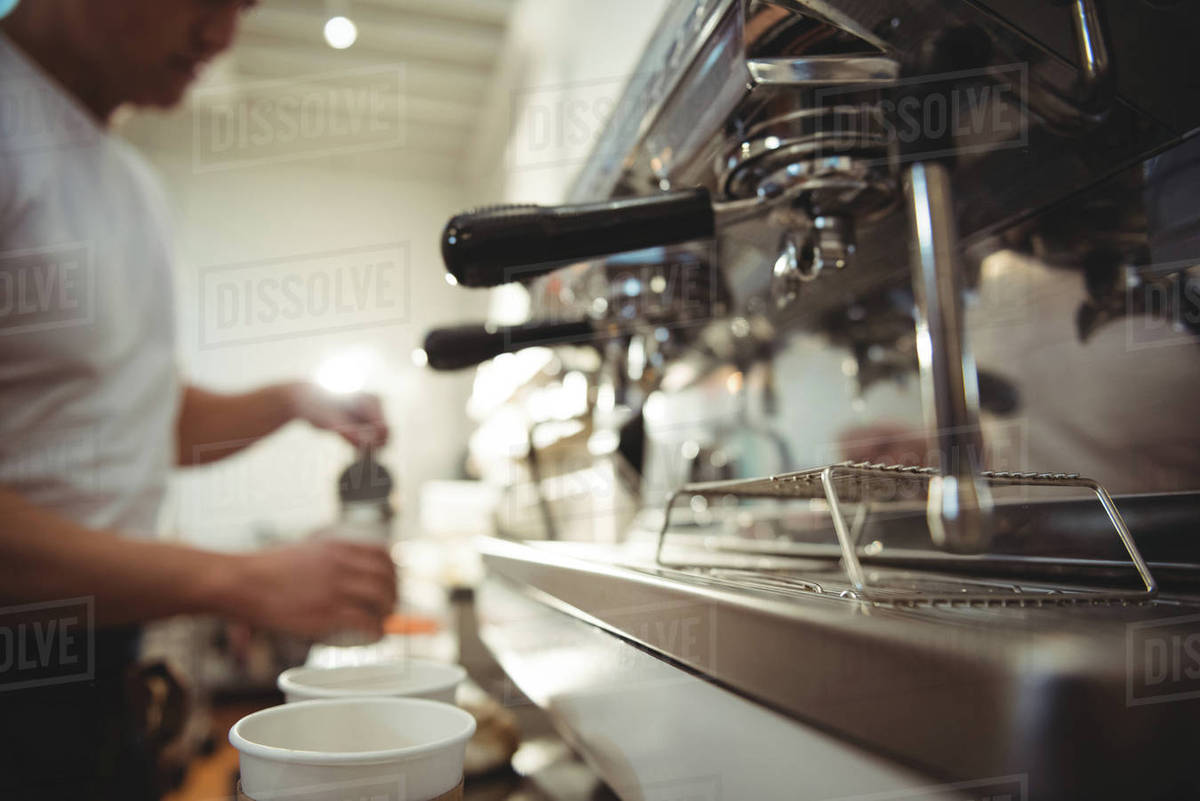 Close Up Of Coffee Machine With Barista Working In Background At