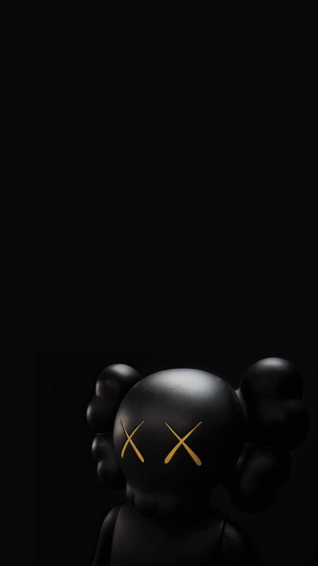 A close-up, dimly lit photograph of a KAWS Companion figure against a black background. The figure's signature X-ed out eyes and minimalist design are highlighted