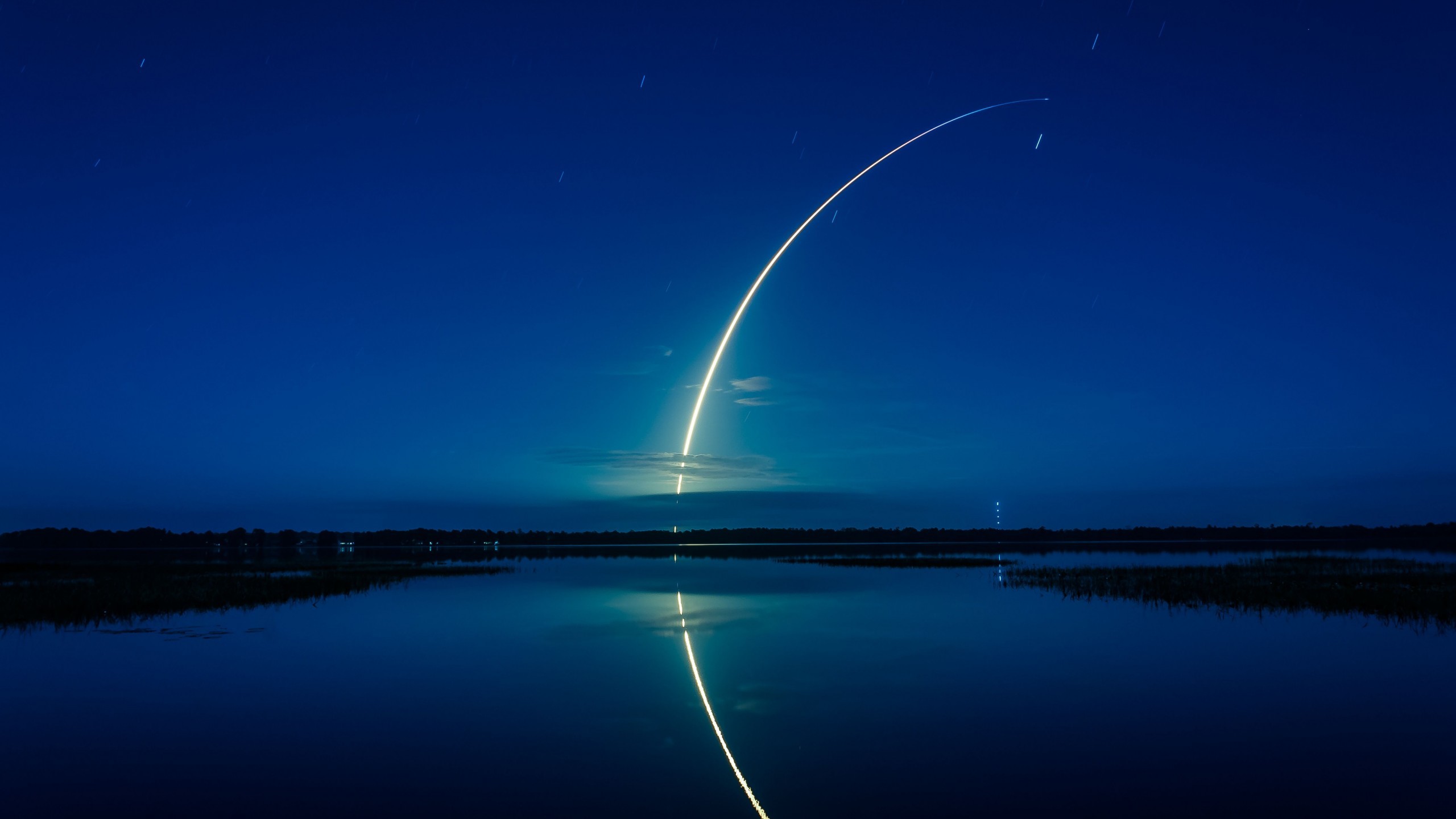 A breathtaking 4K wallpaper of a rocket launching at night, reflected in the still waters below