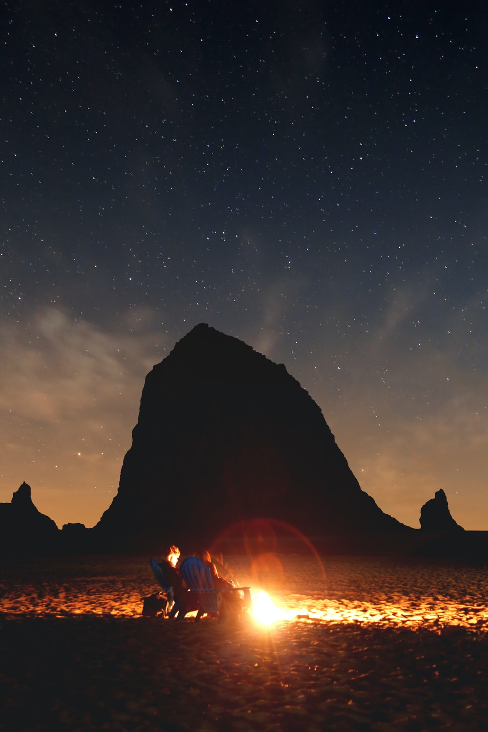 Photo Of Couple Sitting In Front Bonfire Near Mountain