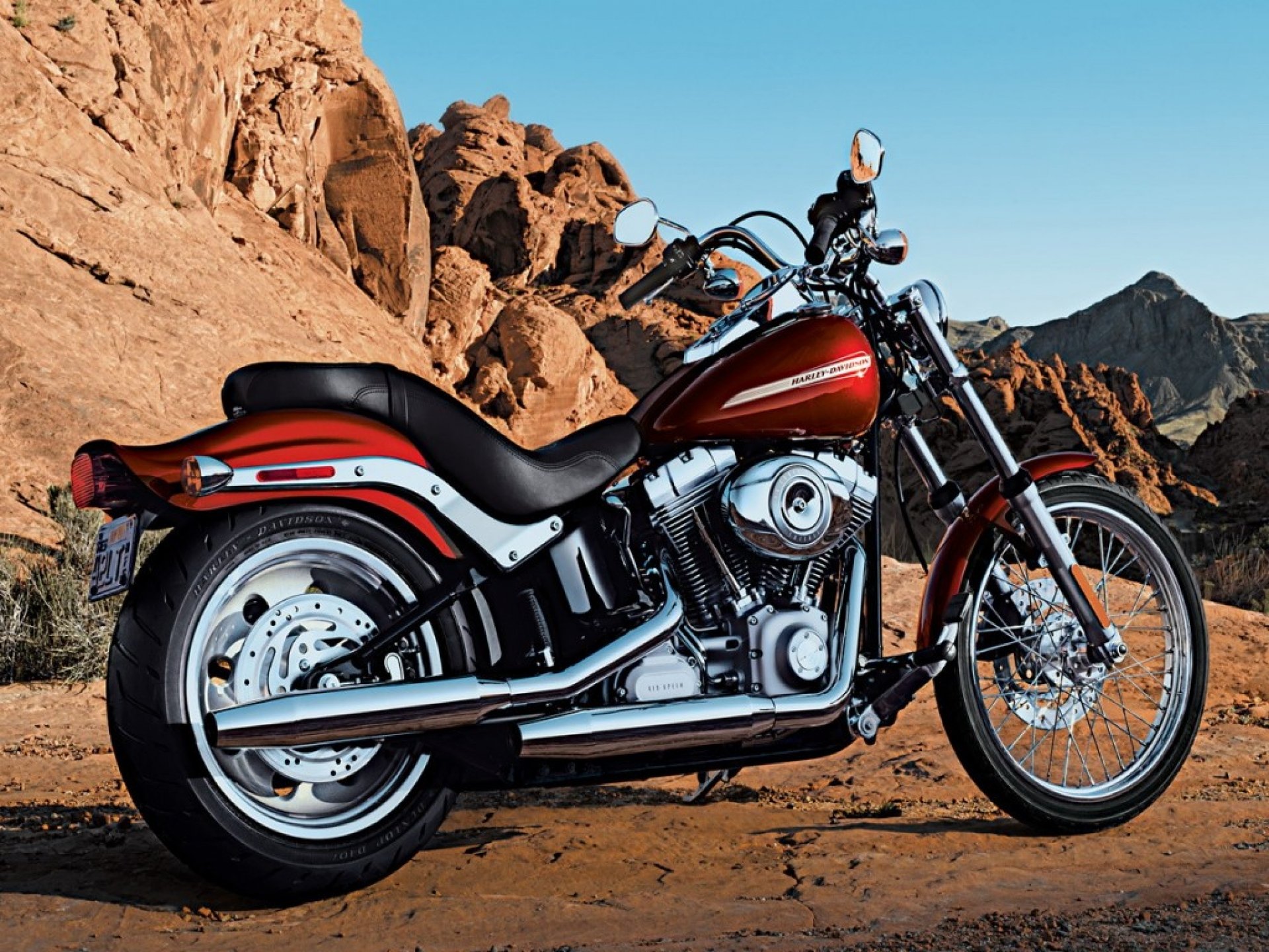 Red Harley-Davidson Softail Deluxe motorcycle parked in a desert landscape