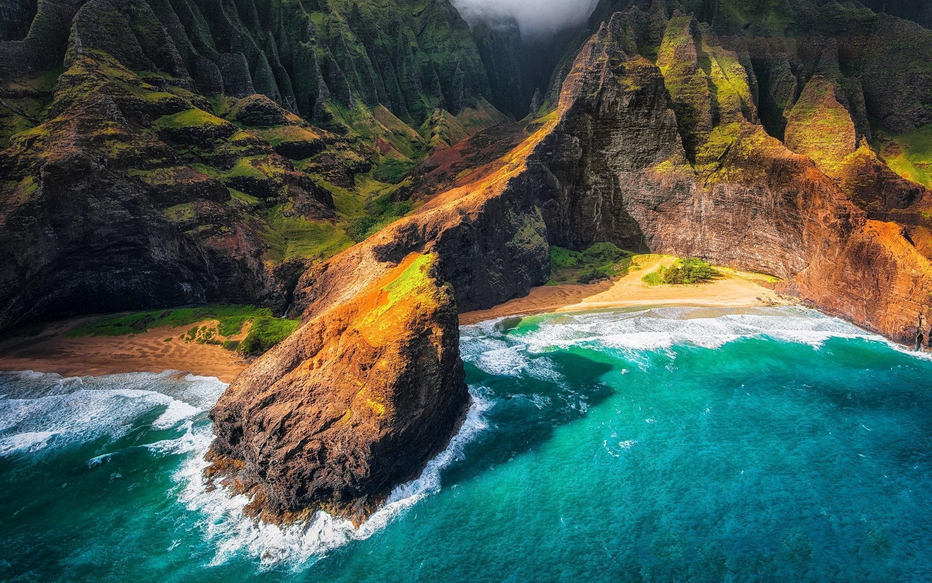 Aerial view of a secluded beach nestled between towering cliffs in Kauai, Hawaii. The turquoise waters crash against the shore, creating a dramatic contrast with the lush green vegetation and the rugged, rocky landscape