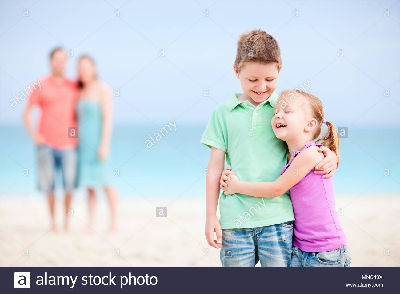 Brother And Sister Embracing Each Other While Parents Standing On