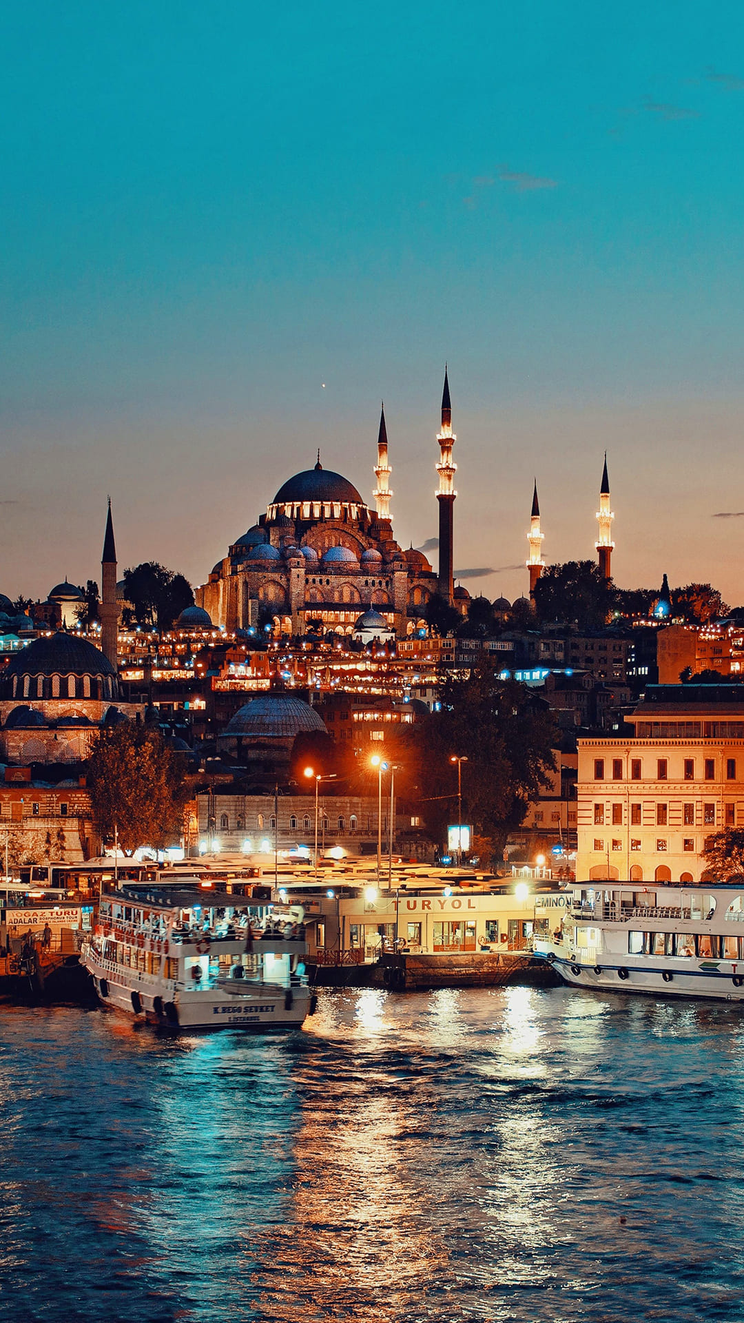A stunning night view of the Süleymaniye Mosque in Istanbul, Turkey, with the illuminated cityscape and the Bosphorus River in the foreground