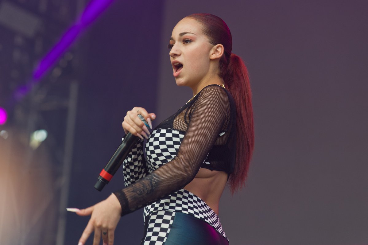 Bhad Bhabie performing live on stage, holding a microphone and wearing a checkered outfit