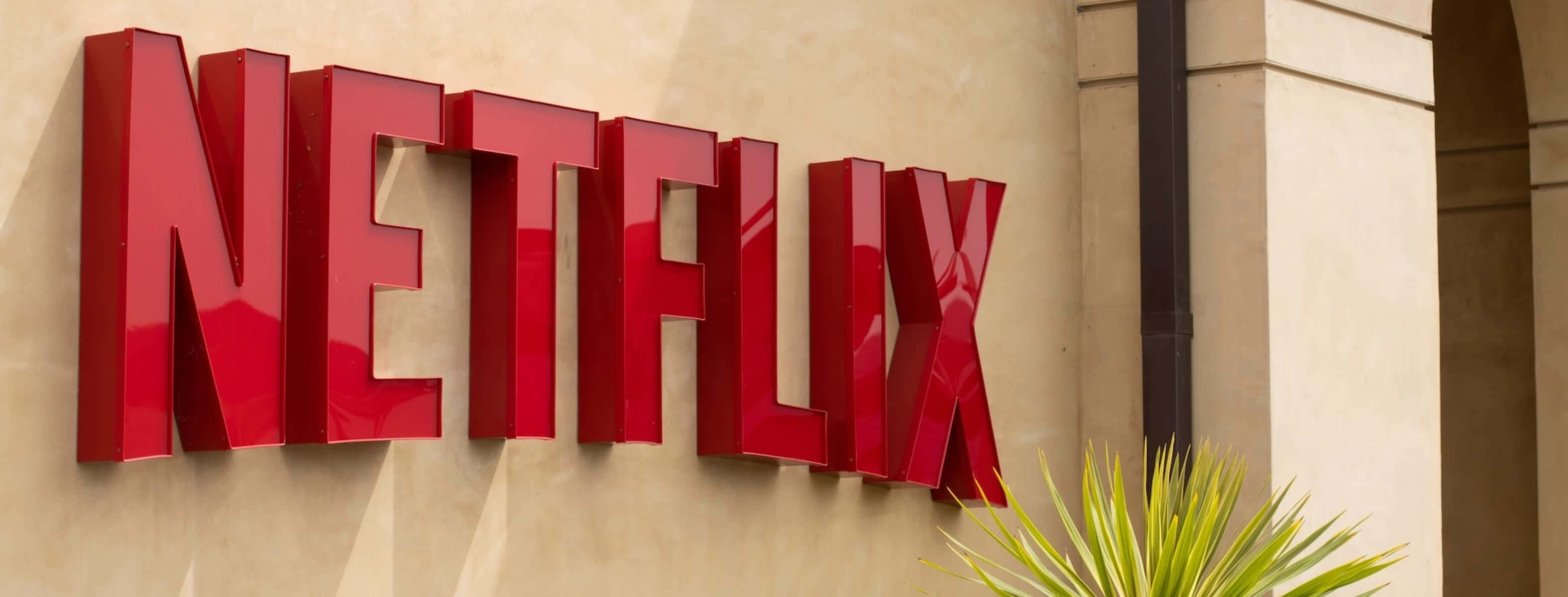 Red Netflix logo against beige wall