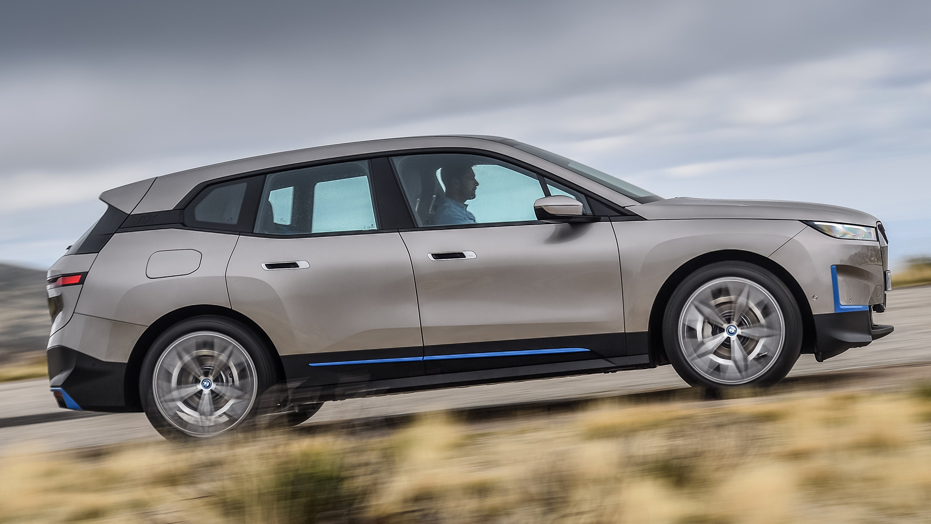 A silver BMW iX electric SUV in motion, showcasing its sleek profile and aerodynamic design