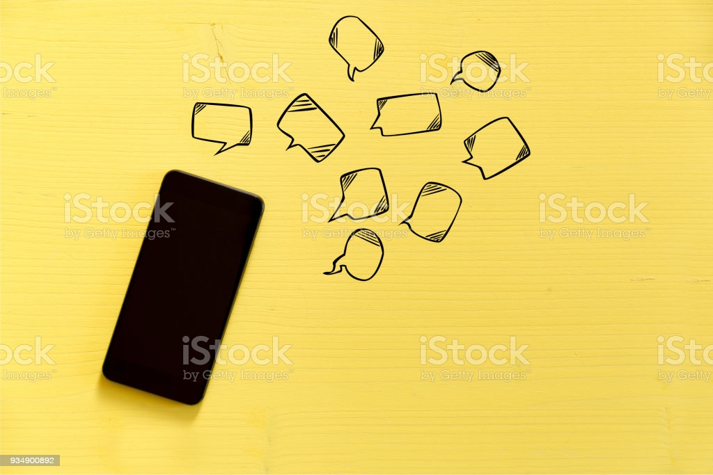 Smartphone On Yellow Background With Text Bubbles Around Messaging