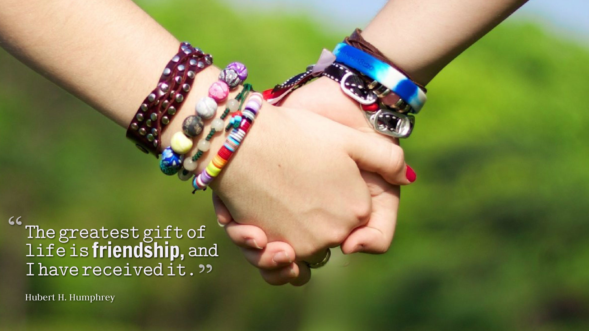 Two hands clasped together, symbolizing friendship, with colorful bracelets and a quote about the importance of friendship