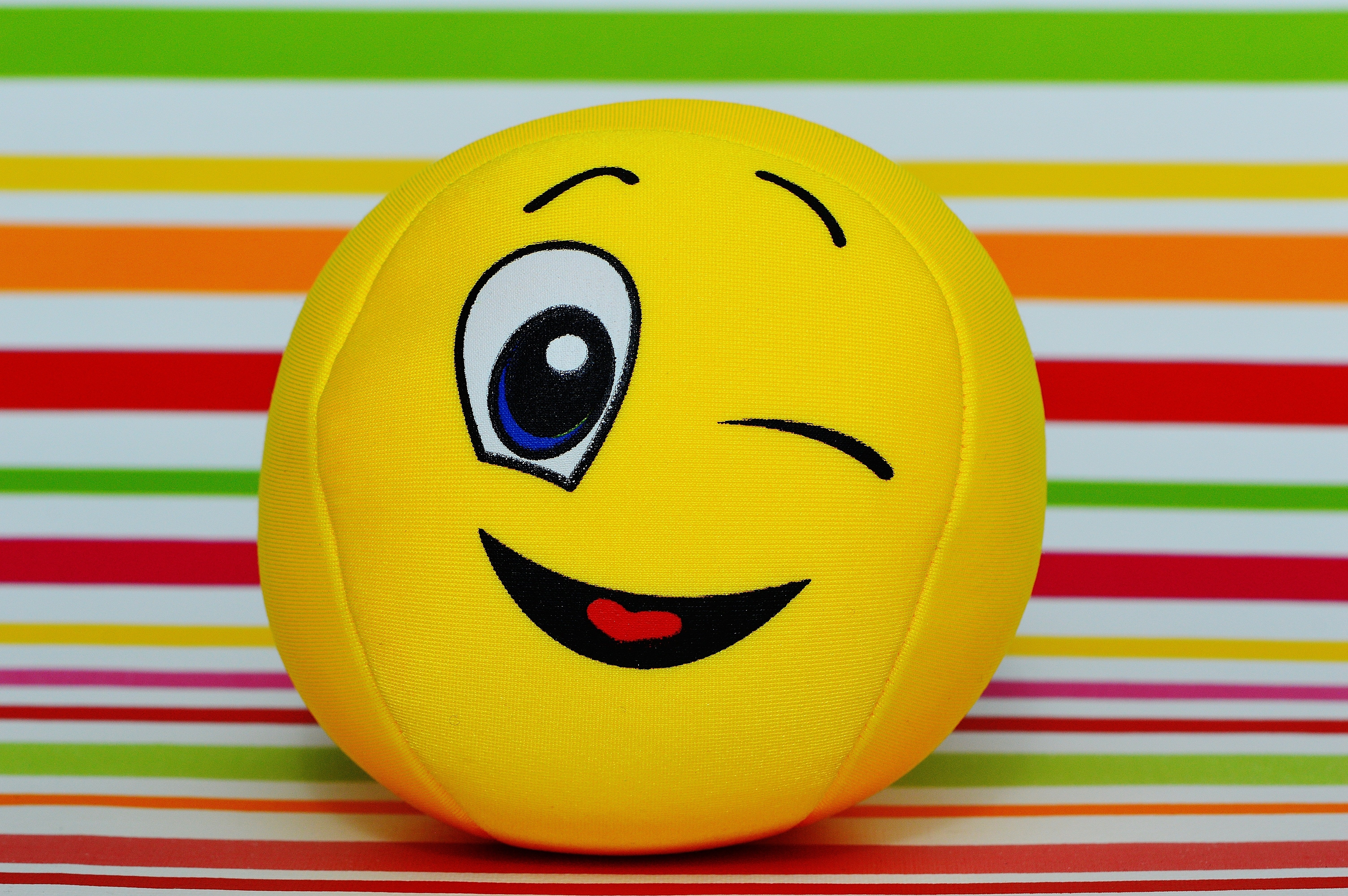 Winking Smiley Ball Plush Toy On Concrete Pavement