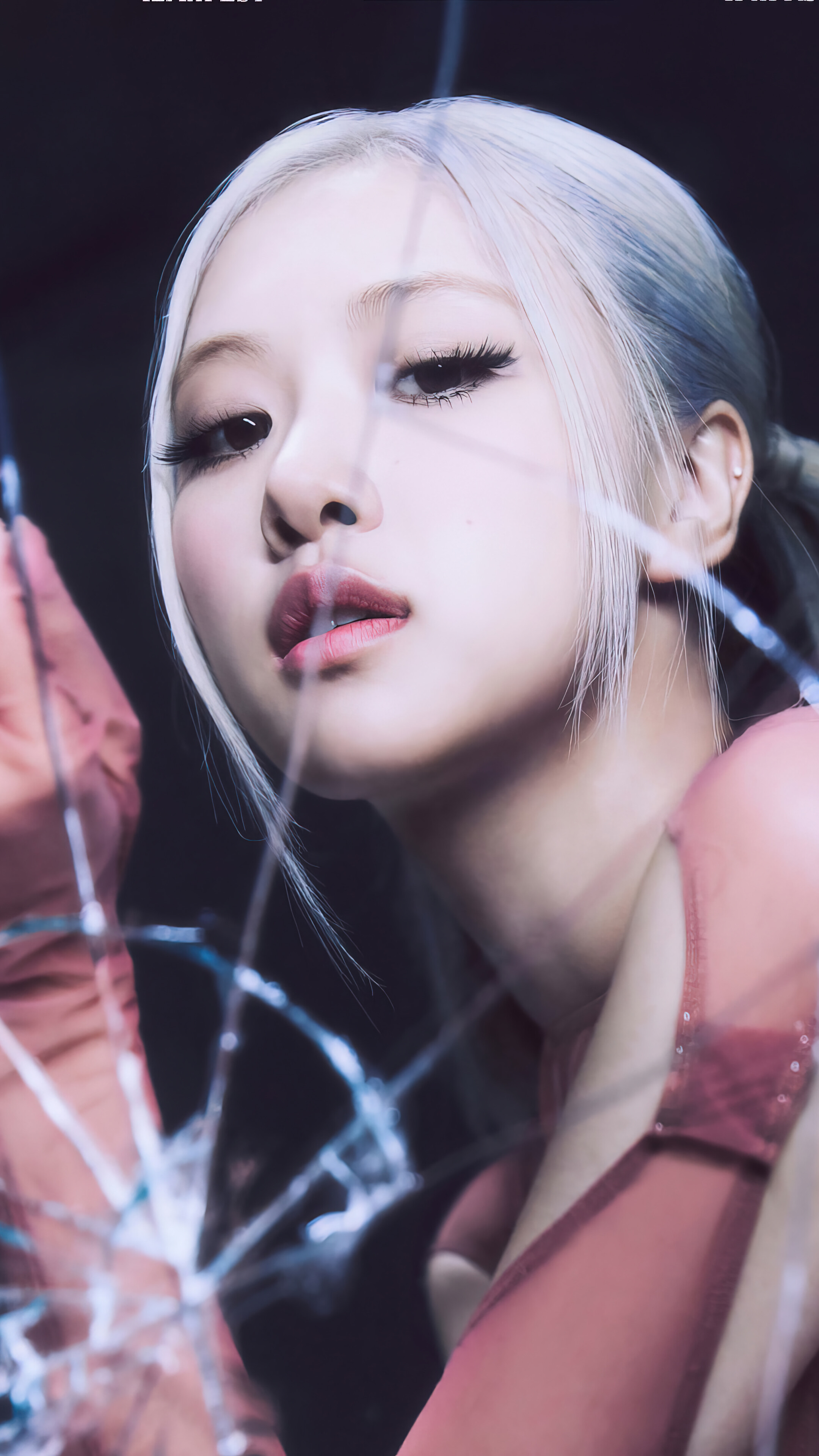 Close-up of Rosé from Blackpink with platinum blonde hair, looking intensely through shattered glass, promotional image for her solo album