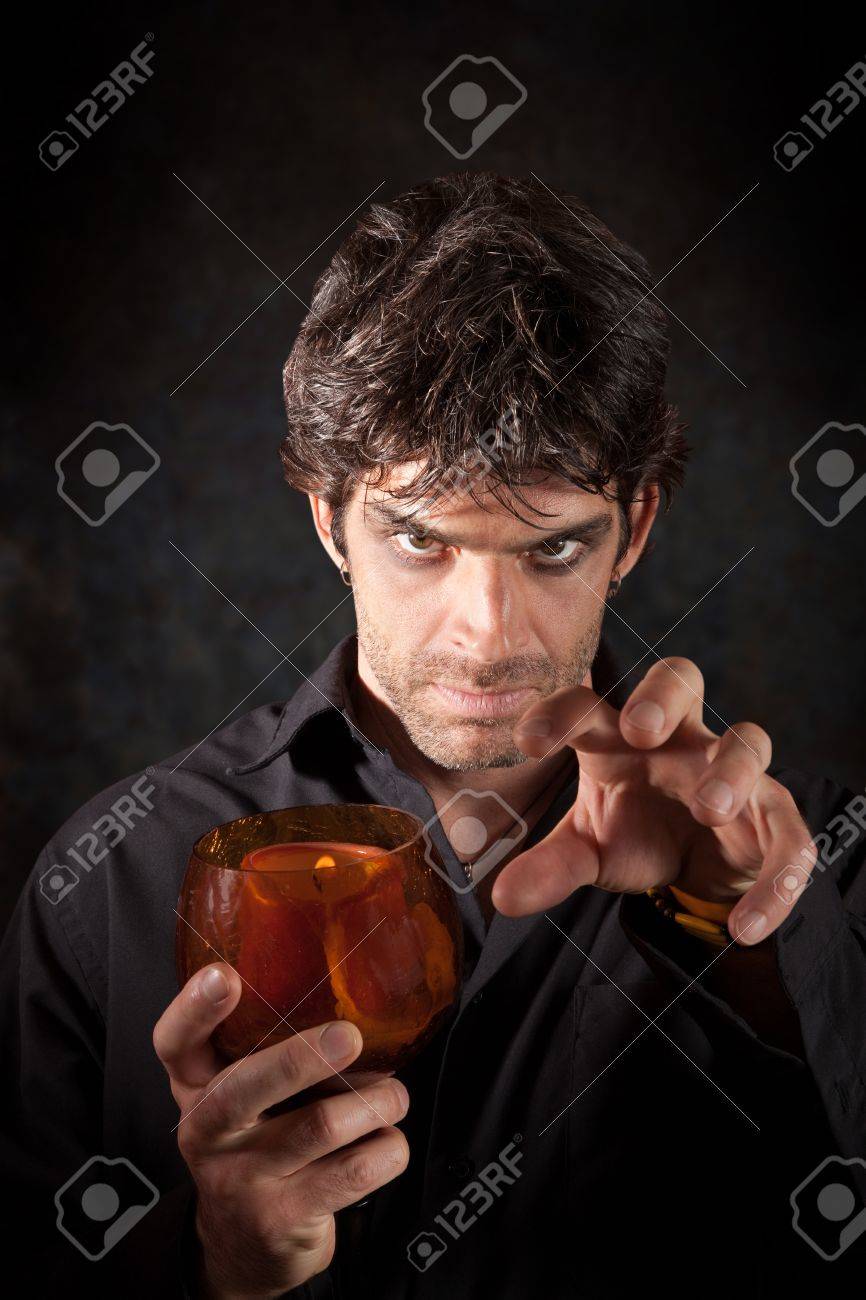 Warlock Holds Candle Over Dark Colored Background Stock Photo